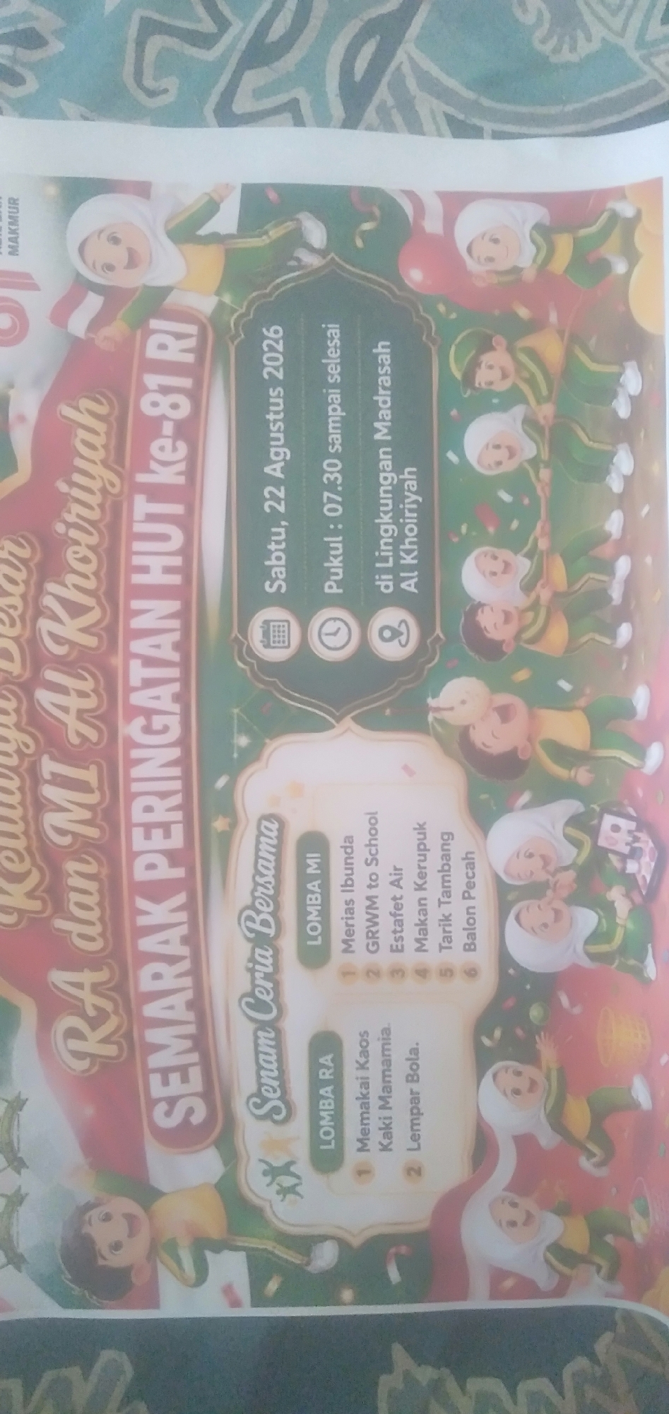 A vertical, low-resolution, and slightly blurry image depicts a festive event poster with cartoon characters. The poster is predominantly green and red, with white lettering. The text "RA dan MI Al Khoiriyah SEMARAK PERINGATAN HUT ke-81 RI" is prominently displayed in large, stylized white font across the left side of the poster. Below this, there is a section with icons and text, indicating event details: a calendar icon with "Sabtu, 22 Agustus 2026", a clock icon with "Pukul : 07.30 sampai selesai", and a person icon with "di Lingkungan Madrasah Al Khoiriyah".
Further to the right, there are two sections listing "LOMBA" (competition) events. The first, labeled "LOMBA MI", includes items like "Merias Ibunda", "GRWM to School", "Estafet Air", "Makan Kerupuk", "Tarik Tambang", and "Balon Pecah". The second, labeled "LOMBA RA", lists "Memakai Kaos Kaki Mamamia" and "Lempar Bola".
The background of the poster is filled with numerous cartoon illustrations of children, most of whom are wearing green and yellow uniforms and white headscarves. They are depicted in various playful activities, including what appears to be a tug-of-war and children jumping. Red and white Indonesian flags are also visible. Confetti and streamers suggest a celebratory atmosphere. The overall design is bright and engaging, typical of an event poster aimed at children and families.
The poster is likely located in Plemahan, Indonesia, as indicated by the specific details on the poster, suggesting a local celebration at an educational institution named Al Khoiriyah. The "HUT ke-81 RI" refers to the 81st anniversary of the Republic of Indonesia, placing the event in 2026.