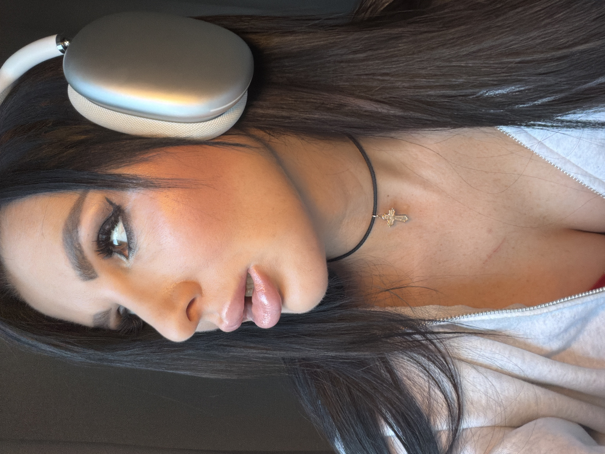 A close-up portrait of a woman. She is wearing headphones and a necklace with a cross pendant. The background is out of focus. There is no information to indicate the location is in Svkh Voronezhskiy, Russia.