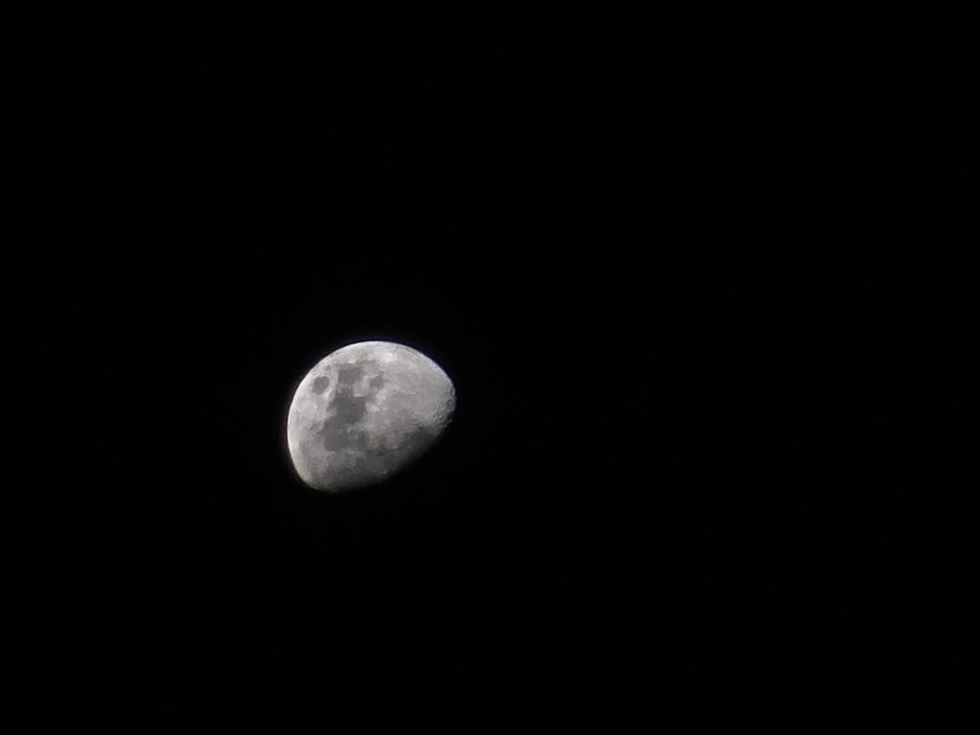 The image shows a waxing gibbous moon against a black sky. No people, actions, or environment beyond the sky are depicted. The location is not identifiable from the provided image.