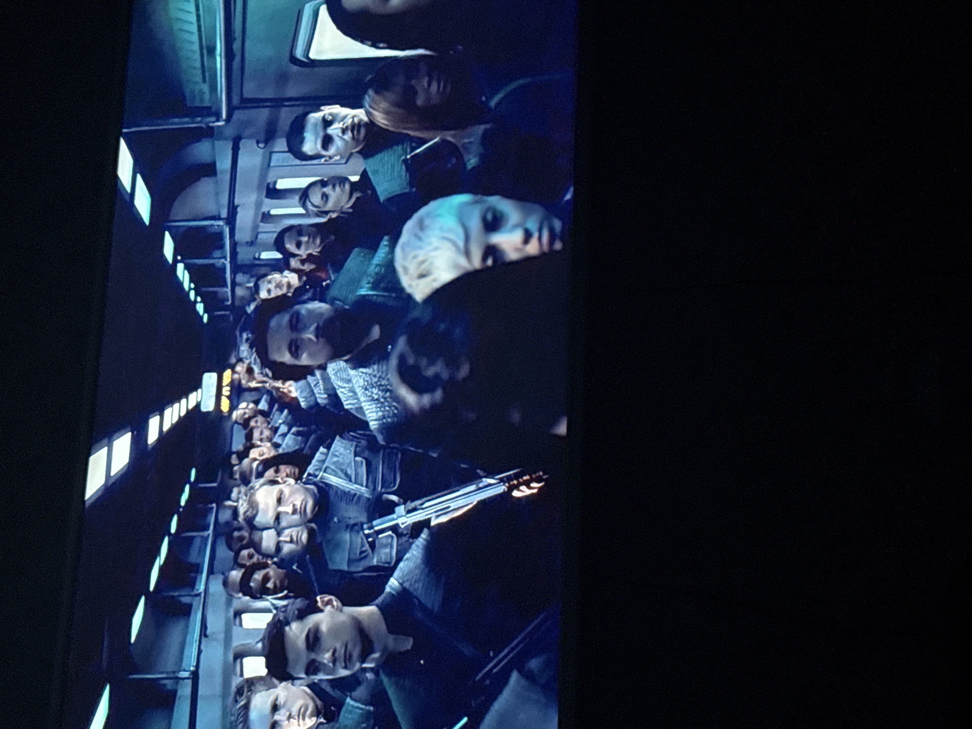 A scene shows many people seated in a vehicle with small windows, lit by small lights. They appear to be armed, and are wearing similar dark blue or black clothing. The location of Mytishchi, Russia is not discernible from this image.