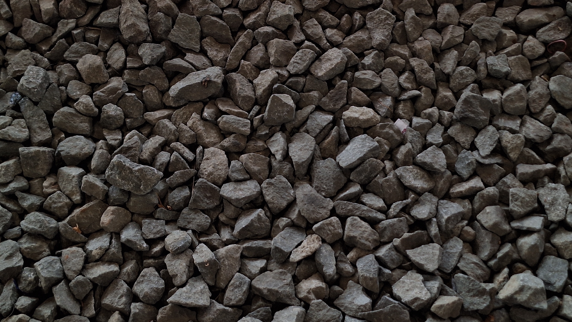 The image depicts a dense collection of gray, irregularly shaped rocks. The rocks vary in size, with some being noticeably larger than others. The composition fills the entire frame, creating a textured surface of stone. No people, specific objects beyond the rocks, actions, or interactions are visible. The environment is a collection of rocks. Karawang, Indonesia is not discernible from the image.