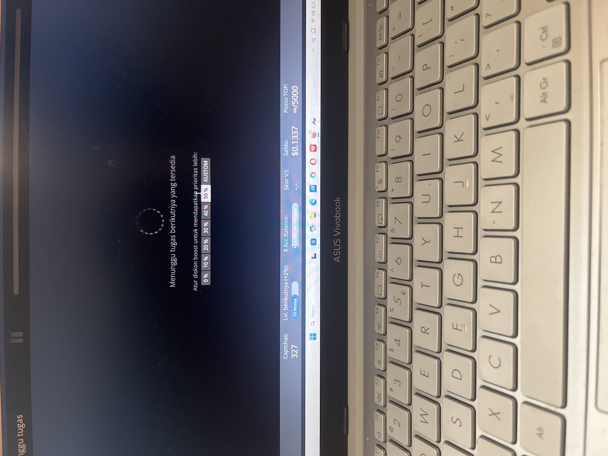 A laptop screen displays a loading animation and text in Indonesian, indicating a waiting status. Below the animation, a message reads "Atur diskon boost untuk mendapatkan prioritas lebih:" followed by selectable percentage options (0%, 10%, 20%, 30%, 40%, 50%) and a "KUSTOM" (custom) option. Further down, a status bar shows "Captchas: 327," "Lvl. berikutnya (+2%): 33 tersisa," "$ Acc. Balance: $0.02807 (433 tersisa)," "Skor V3: -.-," "Saldo: $0.1337," and "Posisi TOP: ∞/5000." The lower portion of the image shows a laptop keyboard with the text "ASUS Vivobook" visible on the palm rest. The scene is indoors, likely in a home or office environment, with no specific indicators pointing to the city of Meliau Hulu, Indonesia.