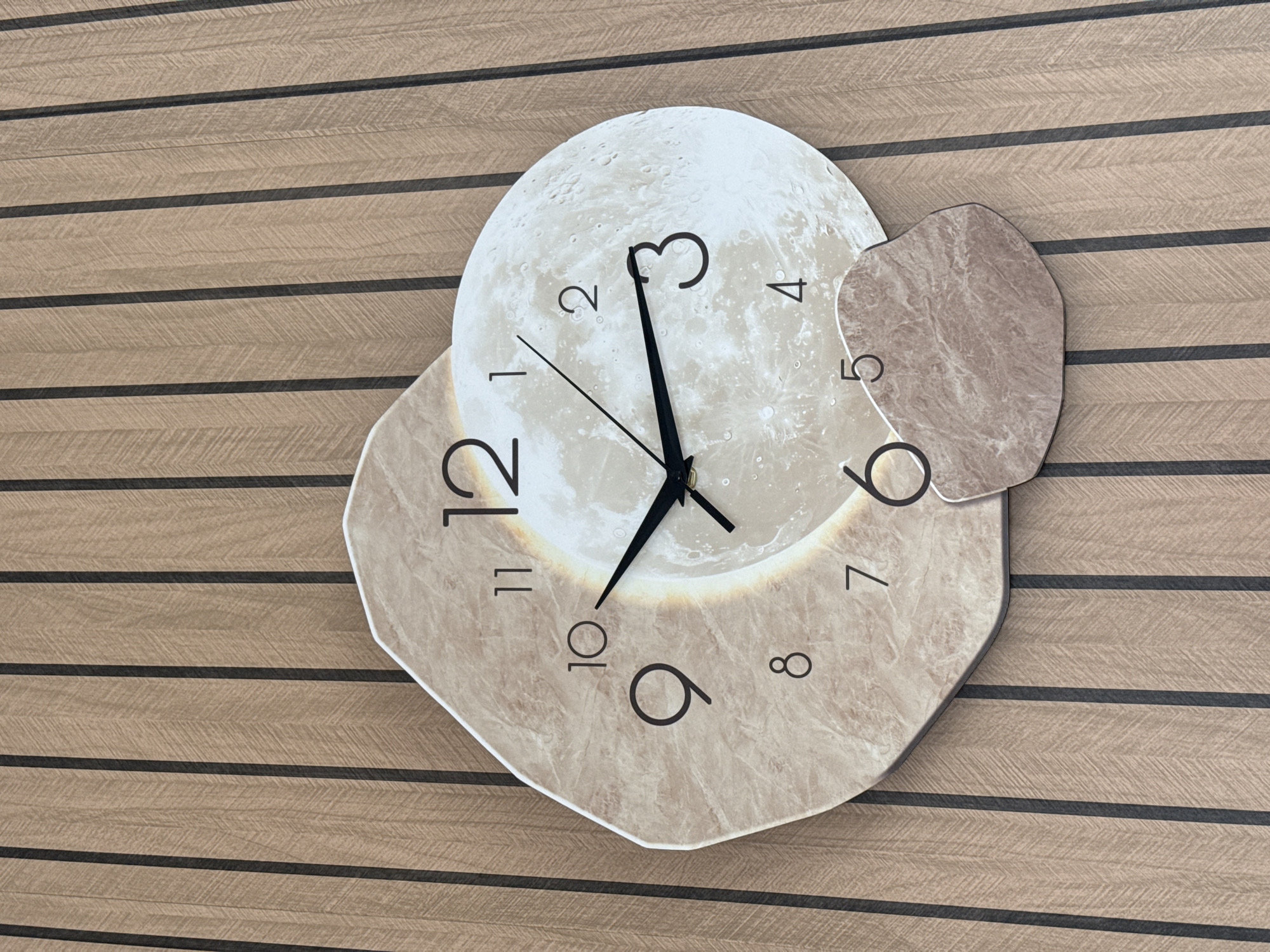 An irregularly shaped wall clock is mounted on a light brown wood-paneled wall in Garmisch-Partenkirchen, Germany. The clock's background consists of three overlapping shapes: a large, irregular, light-toned, marble-patterned base on the left, an overlapping circular depiction of a full moon on the right, and a smaller, irregular, reddish-brown marble-patterned shape at the bottom right. Black numeric markers from 1 to 12 are displayed, with 12, 11, 10, 9, 8, and 7 on the left marble shape, and 1, 2, 3, 4, 5 on the moon shape (number 5 is partially obscured). The clock hands are black, with the hour hand pointing between 9 and 10, and the minute hand pointing directly at 10, indicating the time is approximately 9:50. The wall features vertical dark brown stripes separating light brown sections, each with a subtle chevron wood grain pattern. No individuals are present.