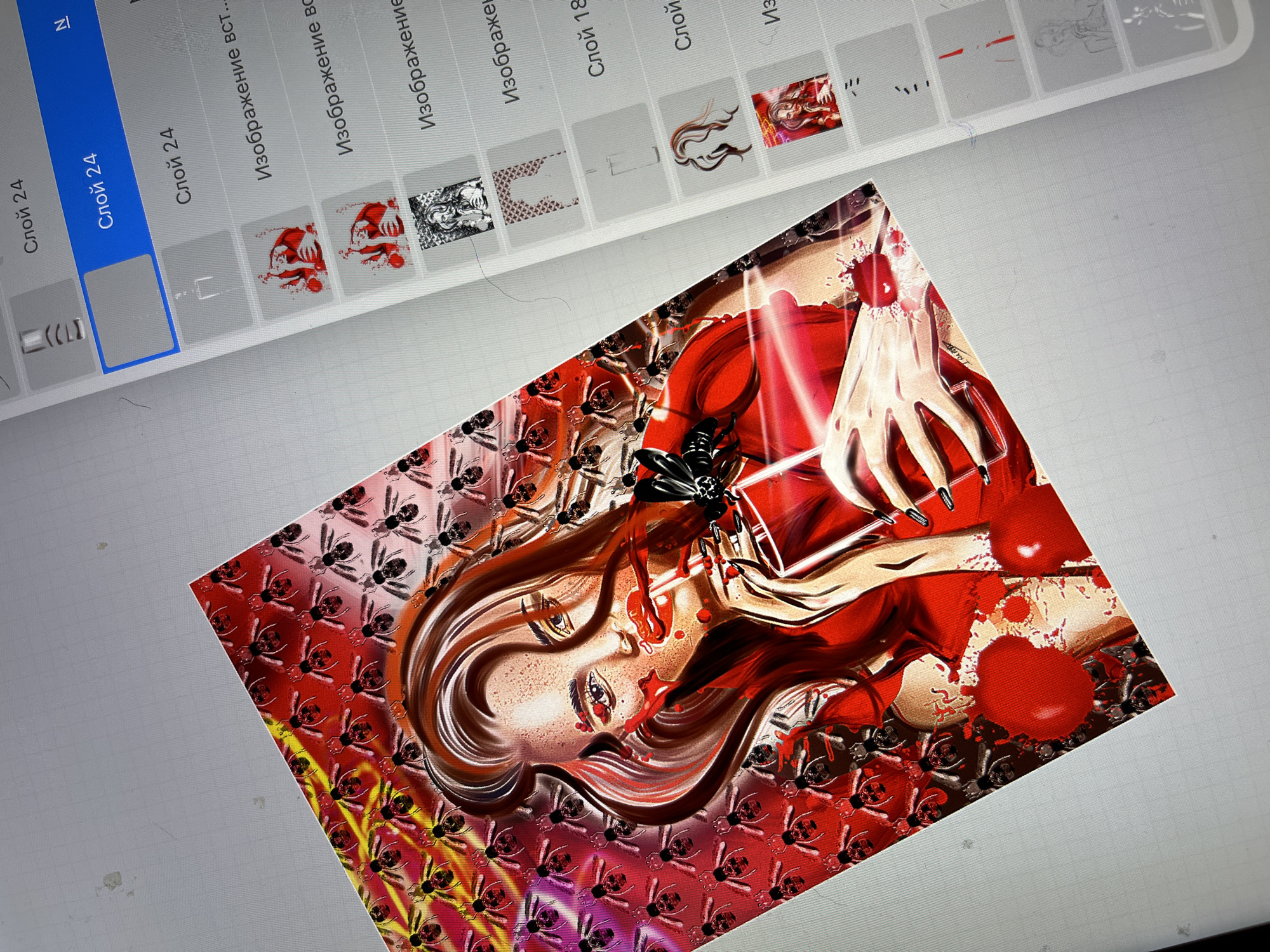 An art piece is displayed on a digital tablet. The artwork features a woman with long brown hair, wearing a red dress and drinking a red beverage from a glass with a straw. The background of the artwork is a red pattern of bees. To the right of the artwork, a digital interface shows a list of layers, with the current layer highlighted as "Слой 24". The tablet is placed on a light-colored, textured surface, possibly a desk. The lighting is bright, illuminating the artwork and the tablet screen.