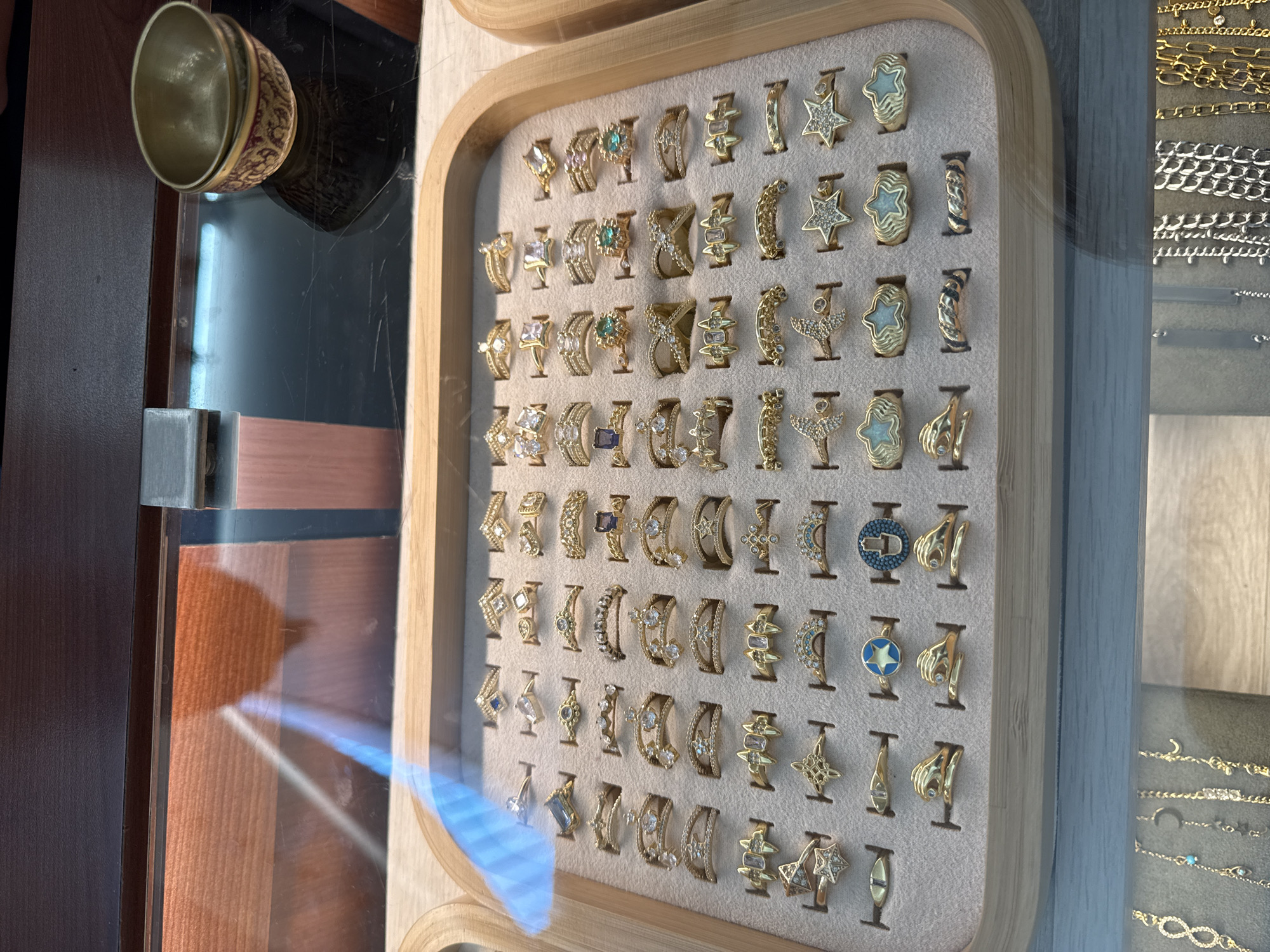 A display case containing jewelry is visible in an indoor setting. The case contains a tray with multiple gold rings arranged in rows. To the right of the rings, a separate display shows a variety of chains and bracelets. The overall environment suggests a retail store or jewelry shop. Based on the details, the location appears to be in the city of Puebla, Mexico.
