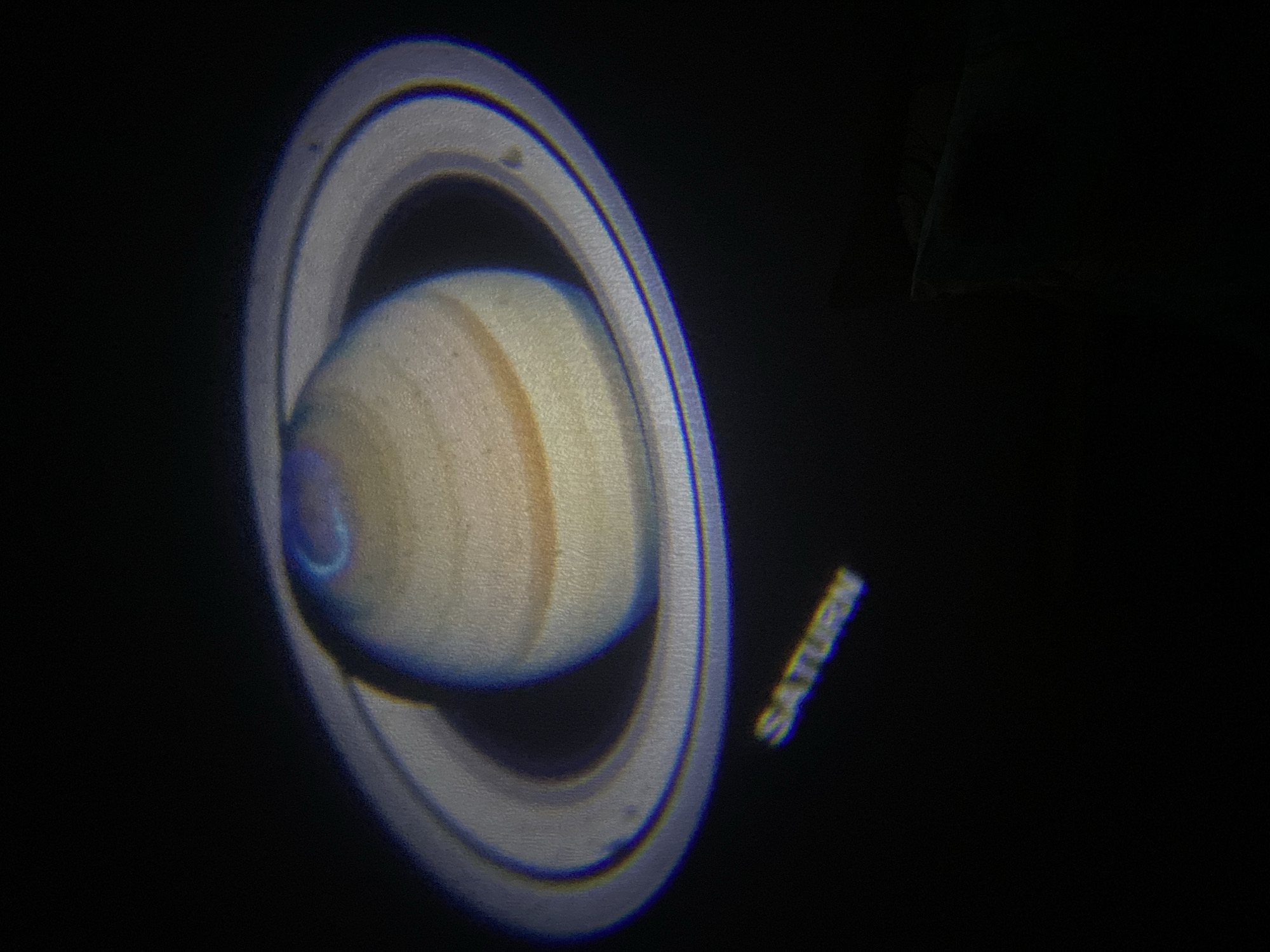 The image depicts the planet Saturn, including its rings, projected onto a dark surface. The word "SATURN" is visible in the bottom right corner of the image, likely the projected label. The location in Saint Petersburg, Russia, is not evident from the visual content of the image.