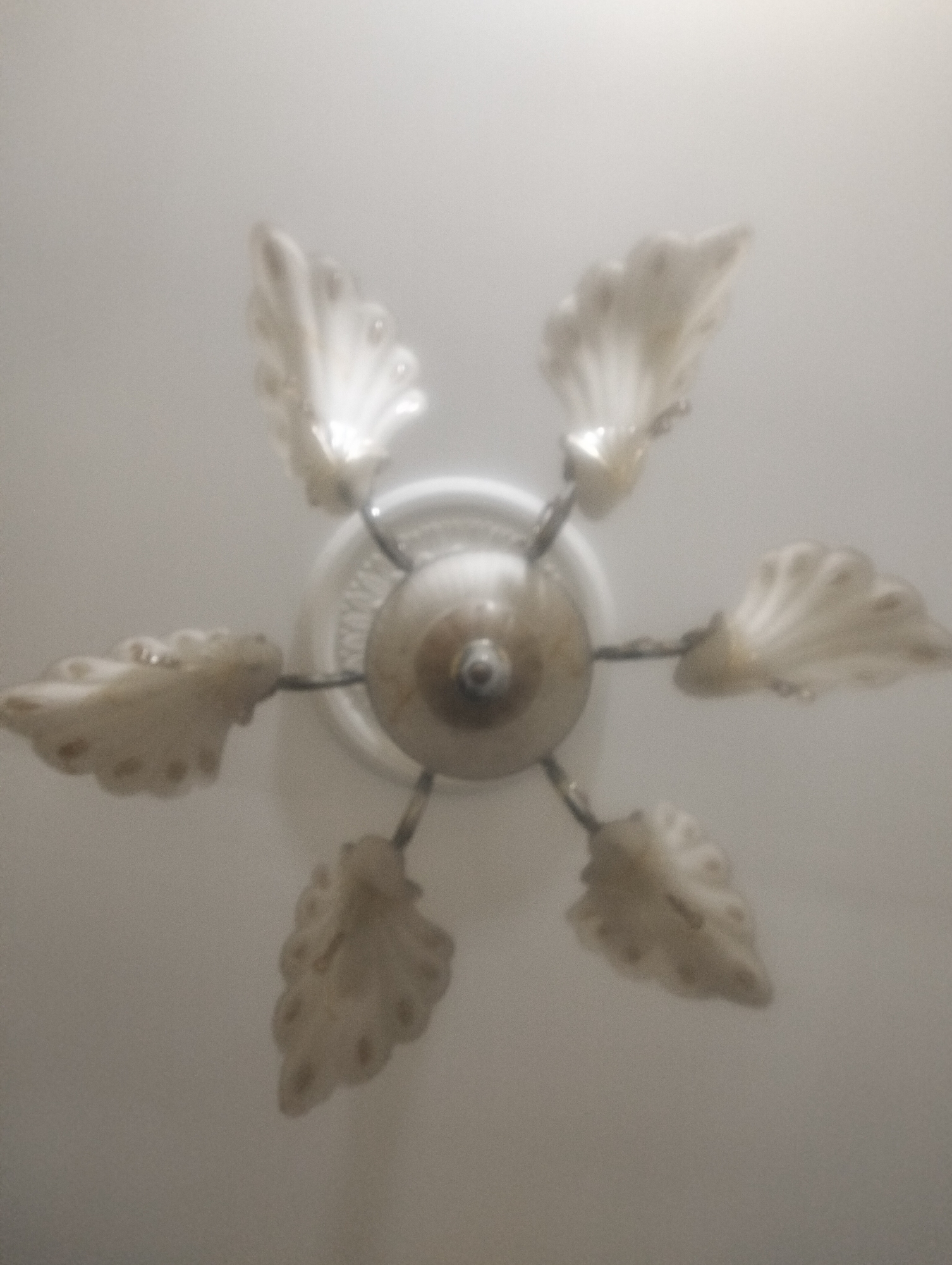 The image shows a ceiling fixture with six white, shell-shaped lampshades arranged in a circular pattern around a central dome. The fixture is mounted on a white ceiling, and the lighting is diffused and soft, indicating it is likely indoors. The overall impression is one of a decorative light fixture, possibly in a home or a public building. Without additional context, it is impossible to determine the specific location within Dumai City, Indonesia.