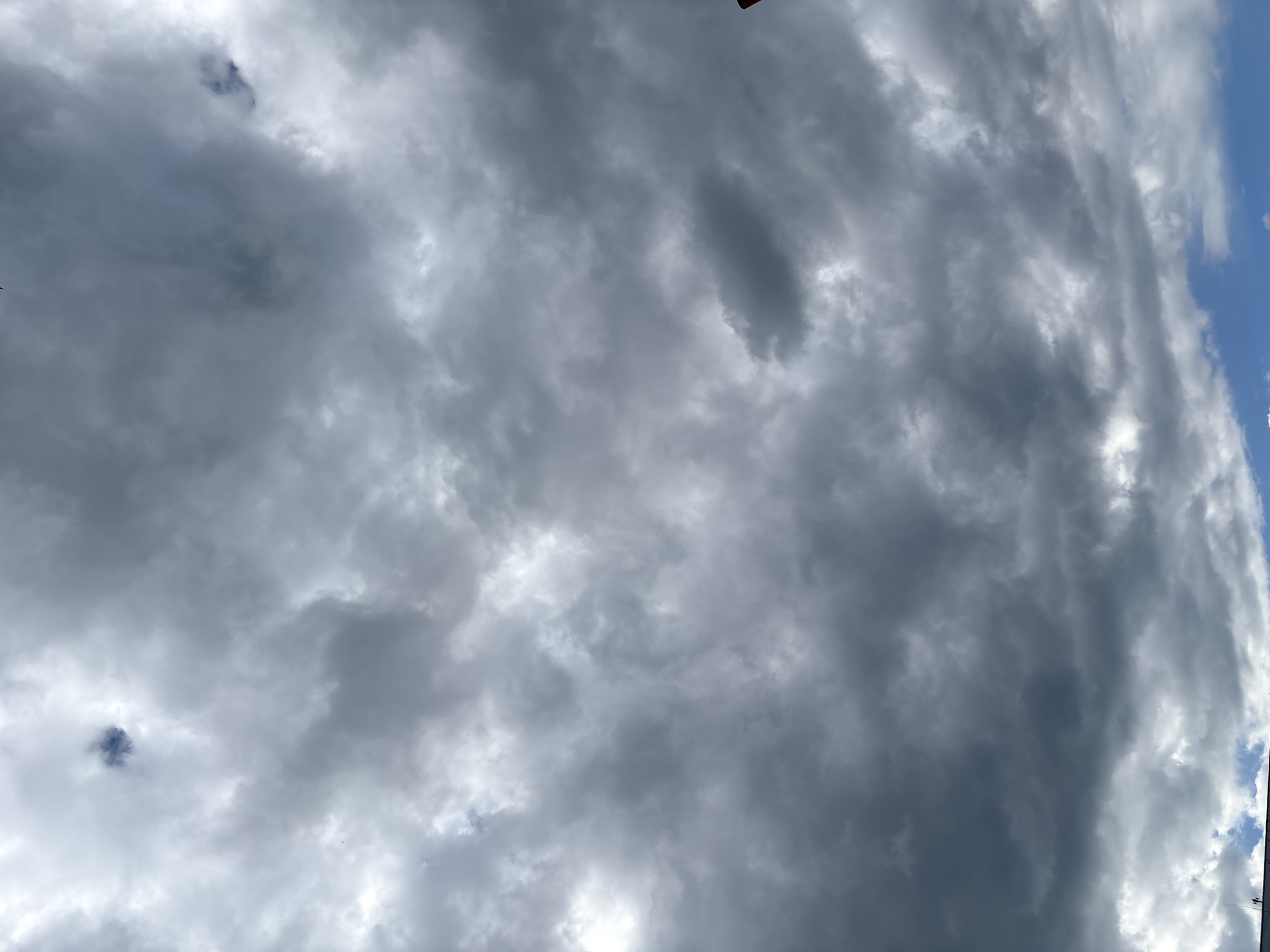 The image shows a cloudy sky with patches of blue visible at the bottom. The clouds are gray and appear to be moving. The image was taken in the city of Chaikovsky, Russia. The scene is a natural outdoor environment, with no people, subjects, or objects clearly identifiable in the image. The weather appears to be overcast with a possibility of rain.