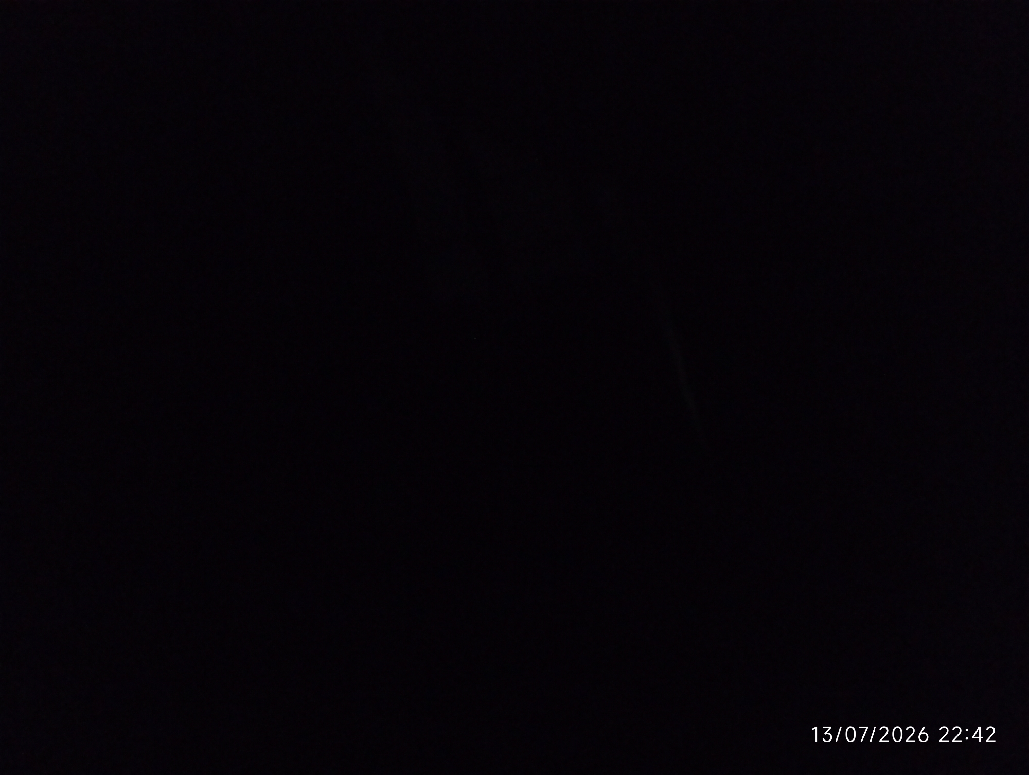 The image is a dark, nighttime photograph. There is a timestamp in the bottom right corner that reads "13/07/2026 22:42". The image is predominantly black, with some very faint, indistinct lighter areas in the upper right quadrant, possibly indicating distant, out-of-focus lights or atmospheric conditions. There is no discernible activity, people, or objects that can be identified with certainty due to the darkness. The location in the city of Bana Stream, Nigeria, cannot be determined from the visual information present in this image.