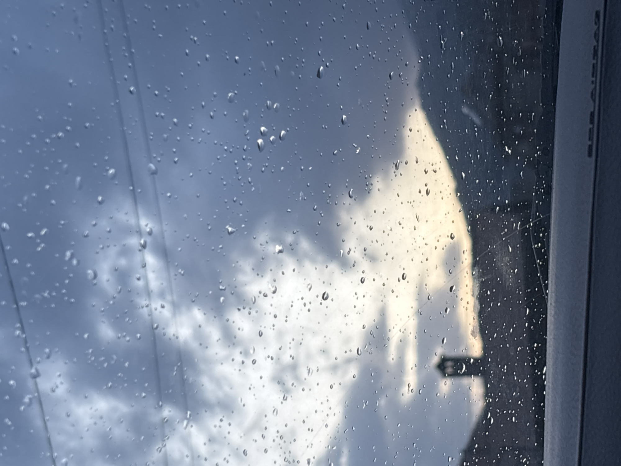 The image shows a rain-streaked window, possibly inside a car, with a view of a cloudy sky and power lines. An arrow-shaped sign is visible through the window. The location of Zlatitsa, Bulgaria is not ascertainable from the image.
