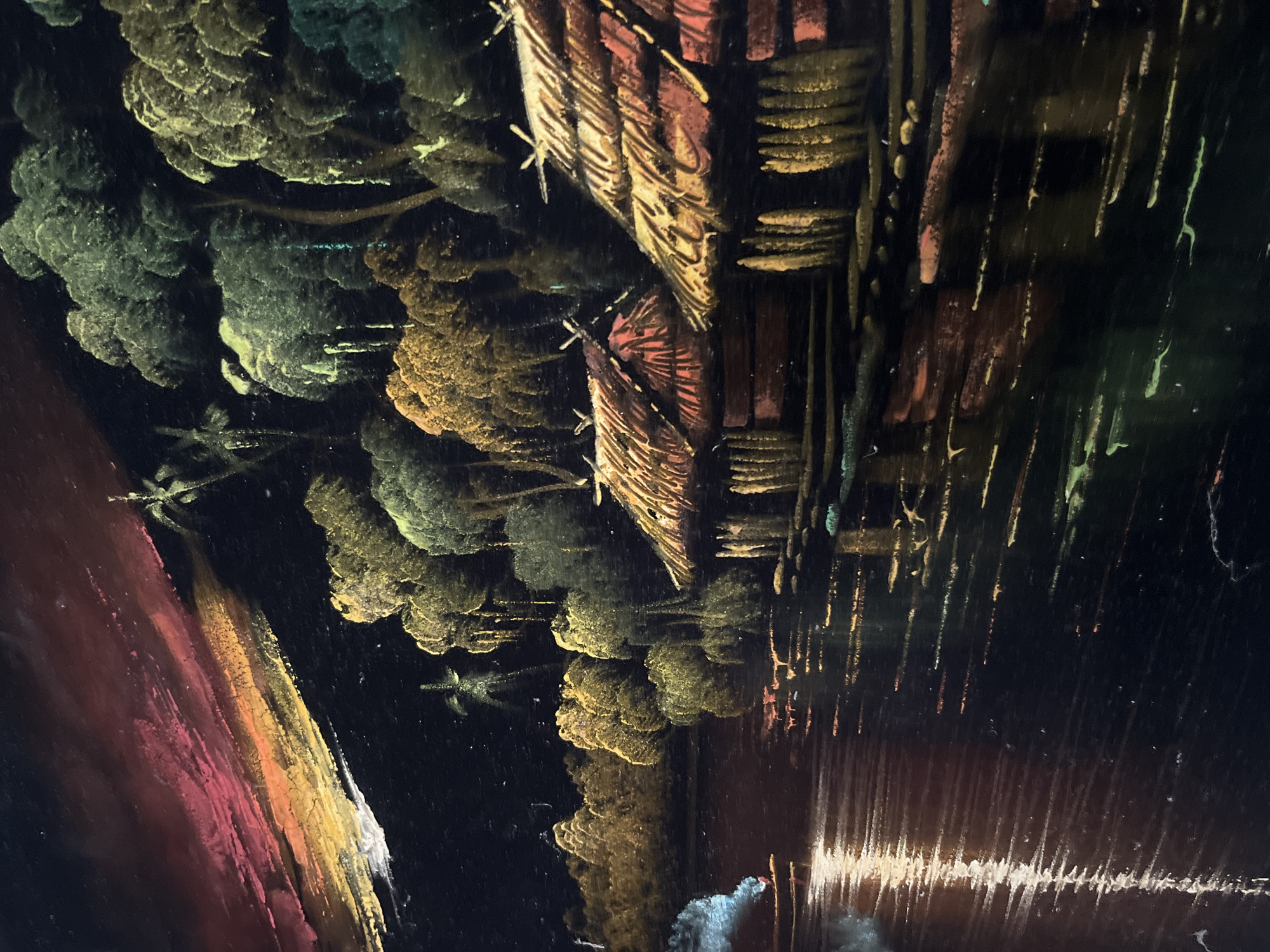 The image depicts a dark, abstract scene resembling a landscape painting. There are clusters of trees in shades of green and yellow/gold, and structures that appear to be buildings with red/brown and yellow tones. The lower portion of the image has streaks of white and a reddish-brown area that suggests a reflection or water. The composition is somewhat distorted. It is not possible to determine if it is located in Tinaquillo, Venezuela. No people, subjects, or interactions are visible.