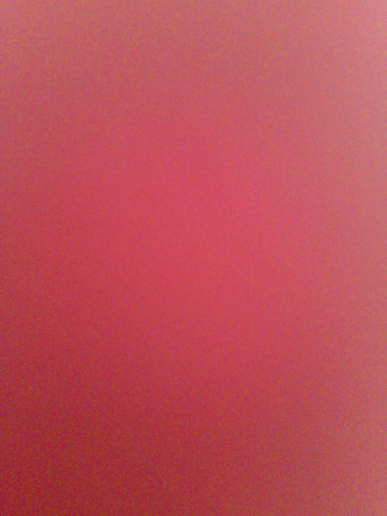 This is a full-frame, top-down, close-up shot of a grainy, speckled, reddish-pink surface. The speckles are smaller, darker red, and golden-yellow. The surface is evenly lit with a slight gradient towards a lighter pink in the top right corner. The image is entirely abstract, with no discernible objects, people, or setting. Therefore, it is not possible to provide details about a location in Meunasahmee, Indonesia.