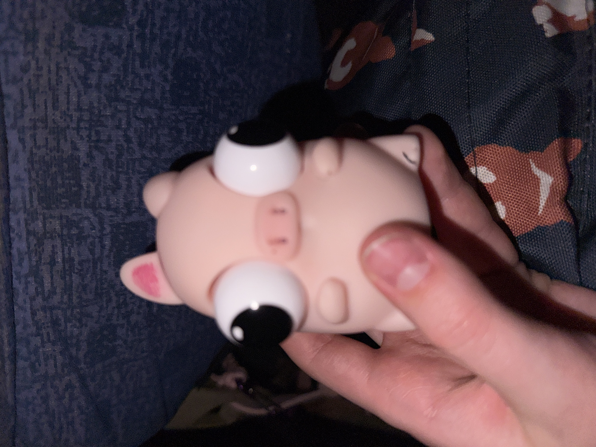 A person is holding a pink, toy pig in their hand. The pig has oversized, cartoonish eyes. The background includes a blue, textured surface and a patterned material with reddish-brown and white shapes. The location is not possible to determine from the image, nor is it possible to determine if this is in Berezniki, Russia.