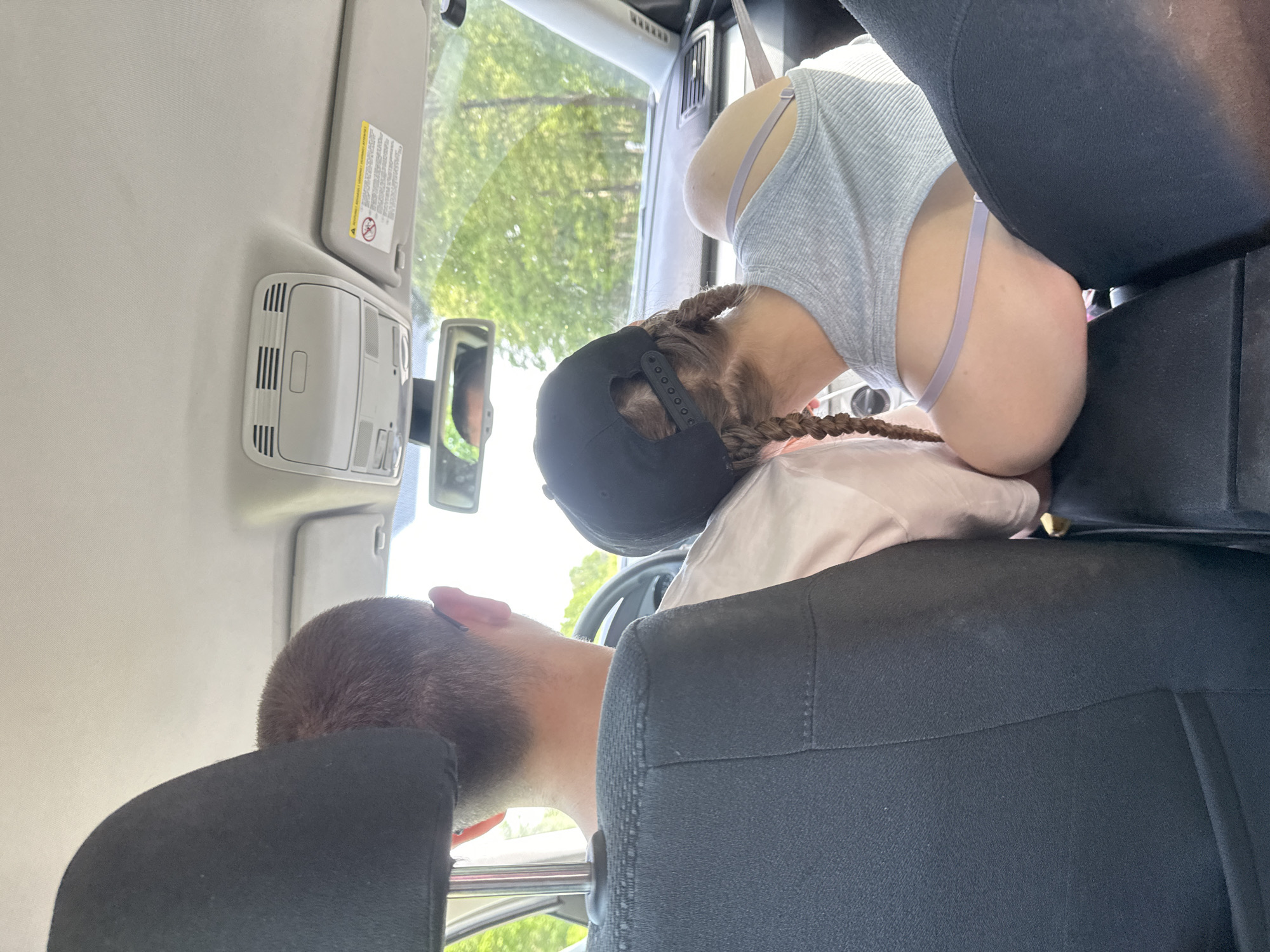 A man and a woman are in the front seats of a car. The man is in the driver's seat, leaning forward with his head near the steering wheel. The woman is in the passenger seat, leaning backwards towards the center console. The location is not specified as Walsrode, Germany, and cannot be determined from the image.