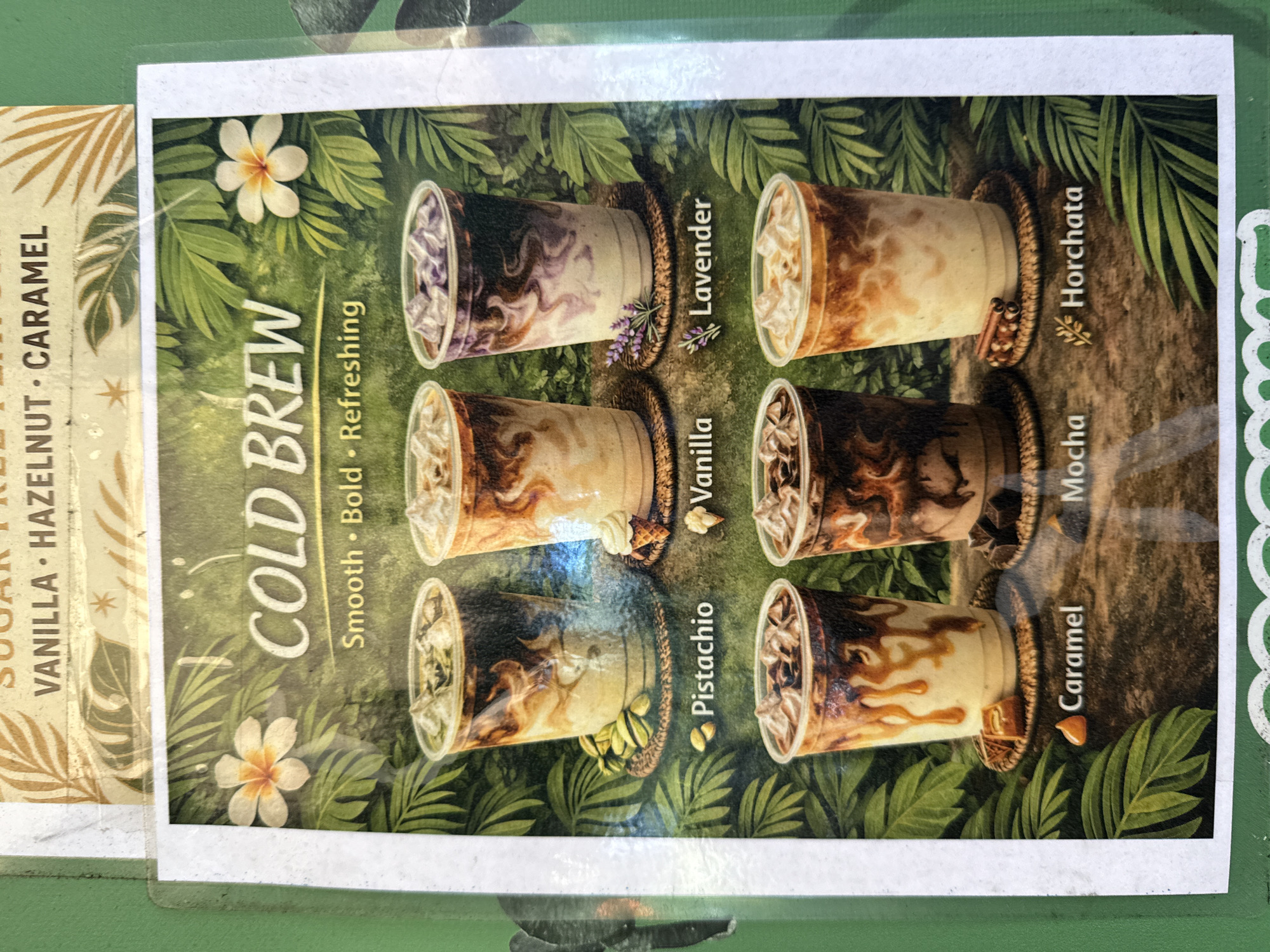 The image is a close-up shot of a printed menu depicting cold brew coffee drinks. The menu features six different flavors of cold brew: Lavender, Horchata, Vanilla, Mocha, Pistachio, and Caramel. Each flavor is represented by a plastic cup filled with a drink that visually corresponds to its name. The cups are arranged in two rows of three, surrounded by a background of lush green tropical foliage and white flowers, creating a vibrant, natural aesthetic. The text "COLD BREW" is prominently displayed in a stylized font, followed by the description "Smooth • Bold • Refreshing". A portion of another menu is visible to the left, displaying a list of sugar-free options: VANILLA, HAZELNUT, and CARAMEL. The location is Davie, United States of America.