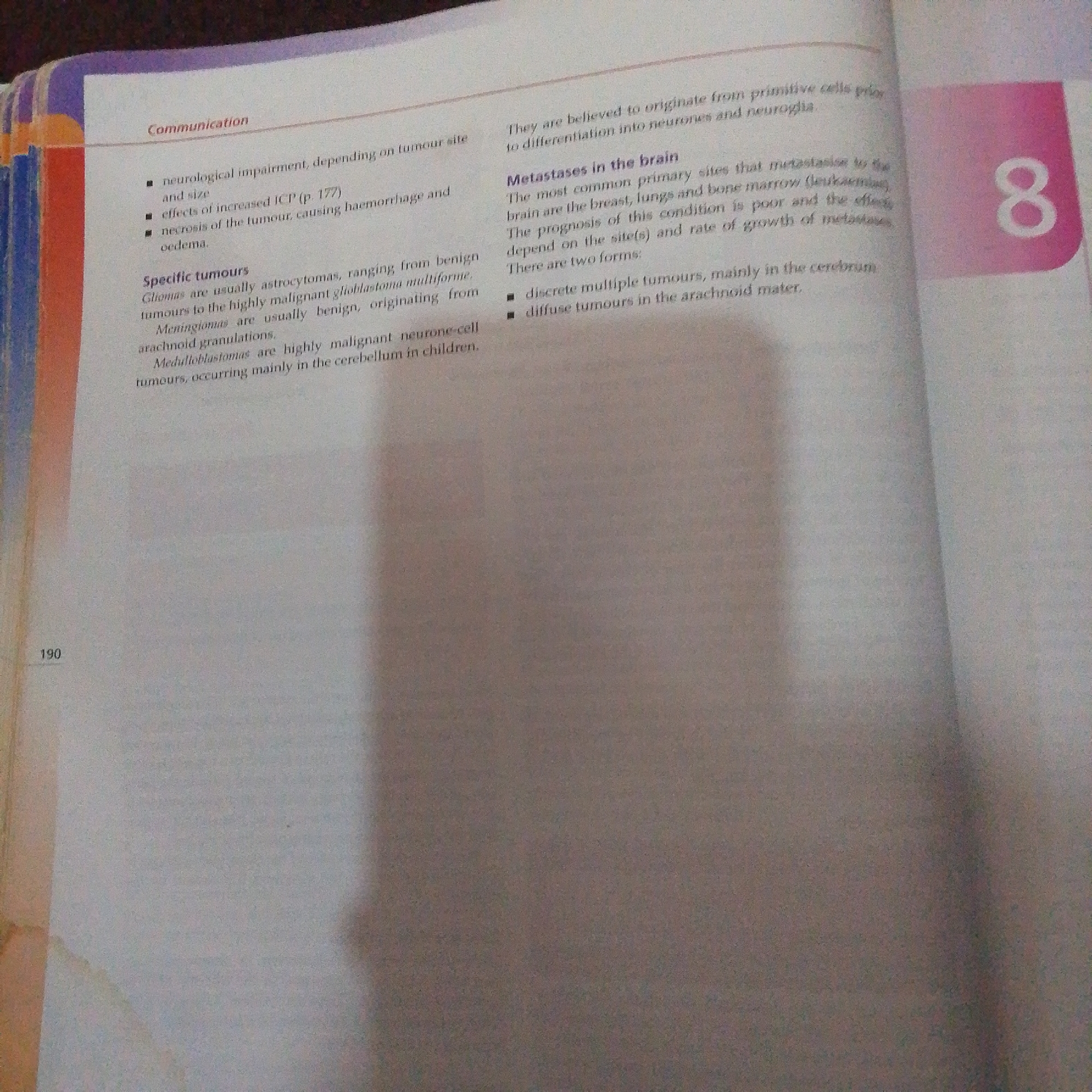 The image shows a close-up view of an open book. The left page has text related to "Communication" and "Specific tumours". It lists neurological impairment, effects of increased ICP, necrosis of the tumour, and types of tumours like gliomas, meningiomas, and medulloblastomas. The right page has a heading "Metastases in the brain" and describes primary sites for metastases. There is a large number "8" in a pink box on the far right. The page number "190" is visible at the bottom left. The book appears to be a medical or scientific text. There is no information within the image that can be used to determine its location in Jalingo, Nigeria.