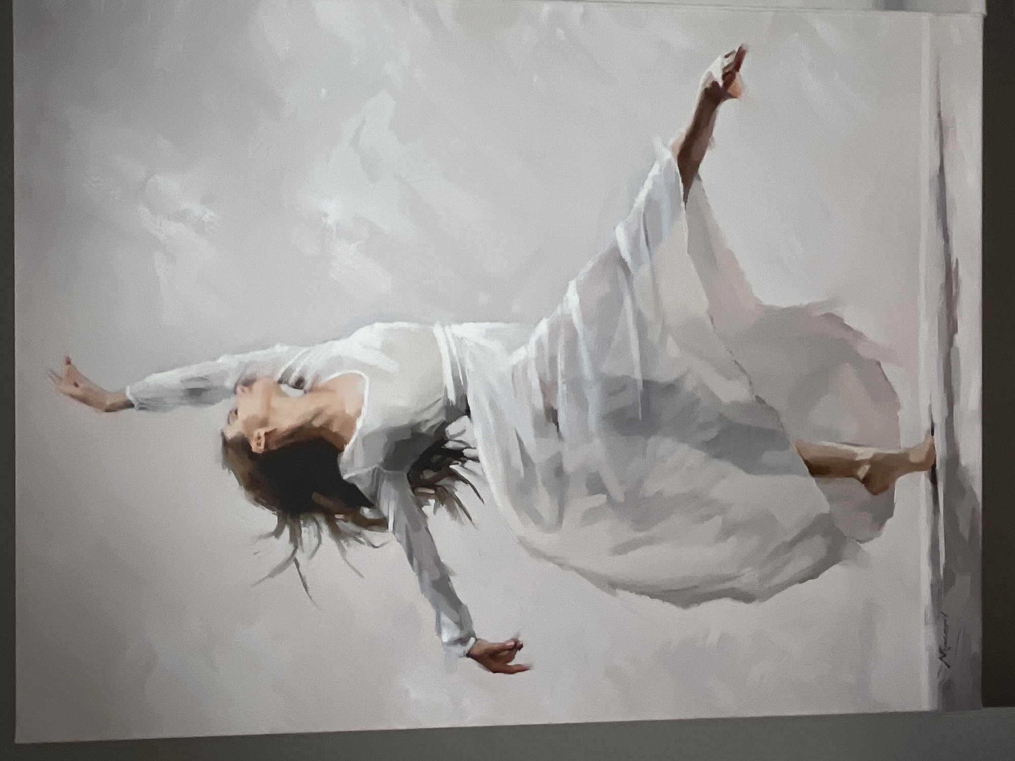 This is a painting of a woman in a white dress dancing. She is captured in mid-motion, with her arms outstretched and her body contorted in a dynamic pose. Her hair is flowing, adding to the sense of movement and grace. The background is simple and abstract, with soft, muted tones that allow the dancer to be the focal point. The painting appears to be oil on canvas, with visible brushstrokes that add texture and depth. There is a signature in the bottom left corner, which reads "Macconi". There is no information provided regarding the location in Kharkiv, Ukraine.