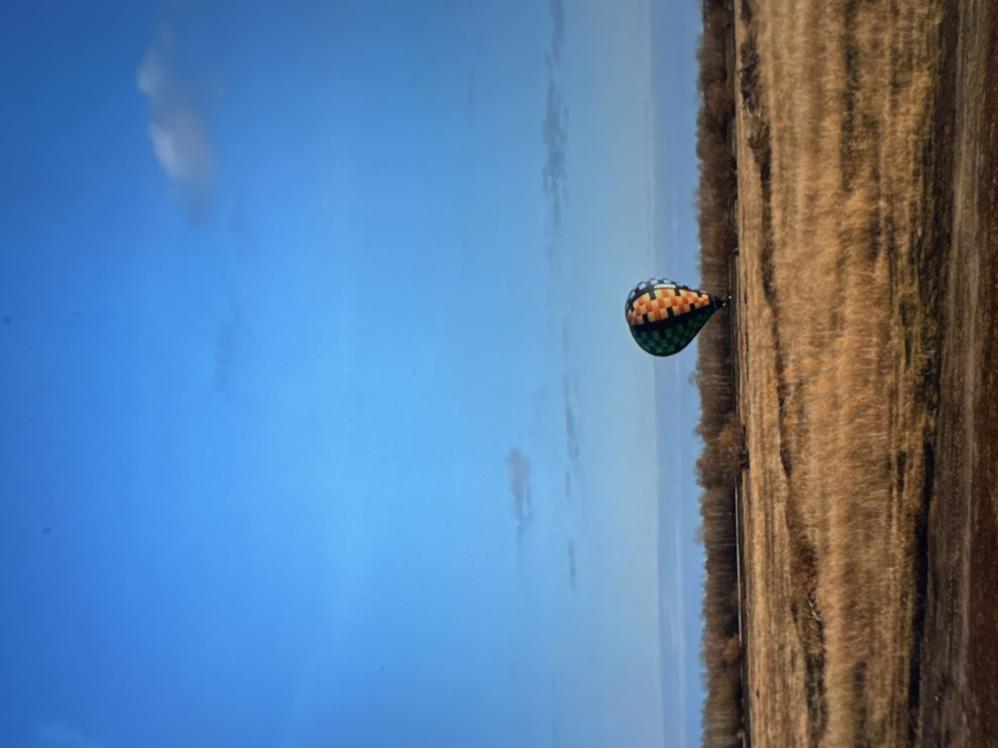 A hot air balloon floats in the sky near a field. The location is Ембаево, Russia.