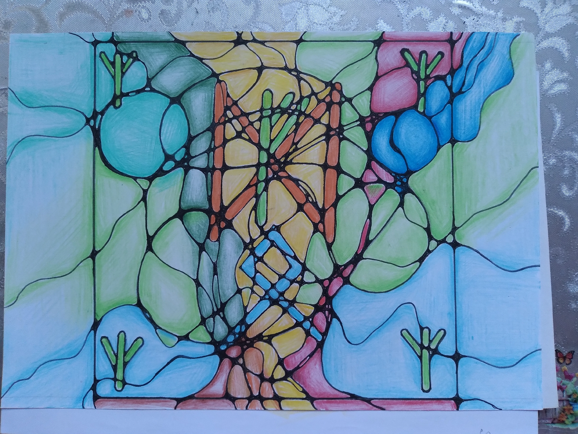 The image is a close-up, eye-level, medium shot of a drawing on white paper, which is laid on a textured, silver-white tablecloth. The drawing is abstract and features a network of interconnected, irregular shapes filled with various colors including light blue, green, yellow, orange, and pink. Thick black lines outline each shape. Within some of the light blue shapes, there are small, green, stylized figures resembling peace signs or simplified stick figures with three protrusions. The drawing appears to be a neurographic art piece, characterized by flowing lines and organic forms. There is no discernible location in the city of Baki, Uzbekistan, depicted in this image. The scene is static, showing only the artwork and its immediate background.
