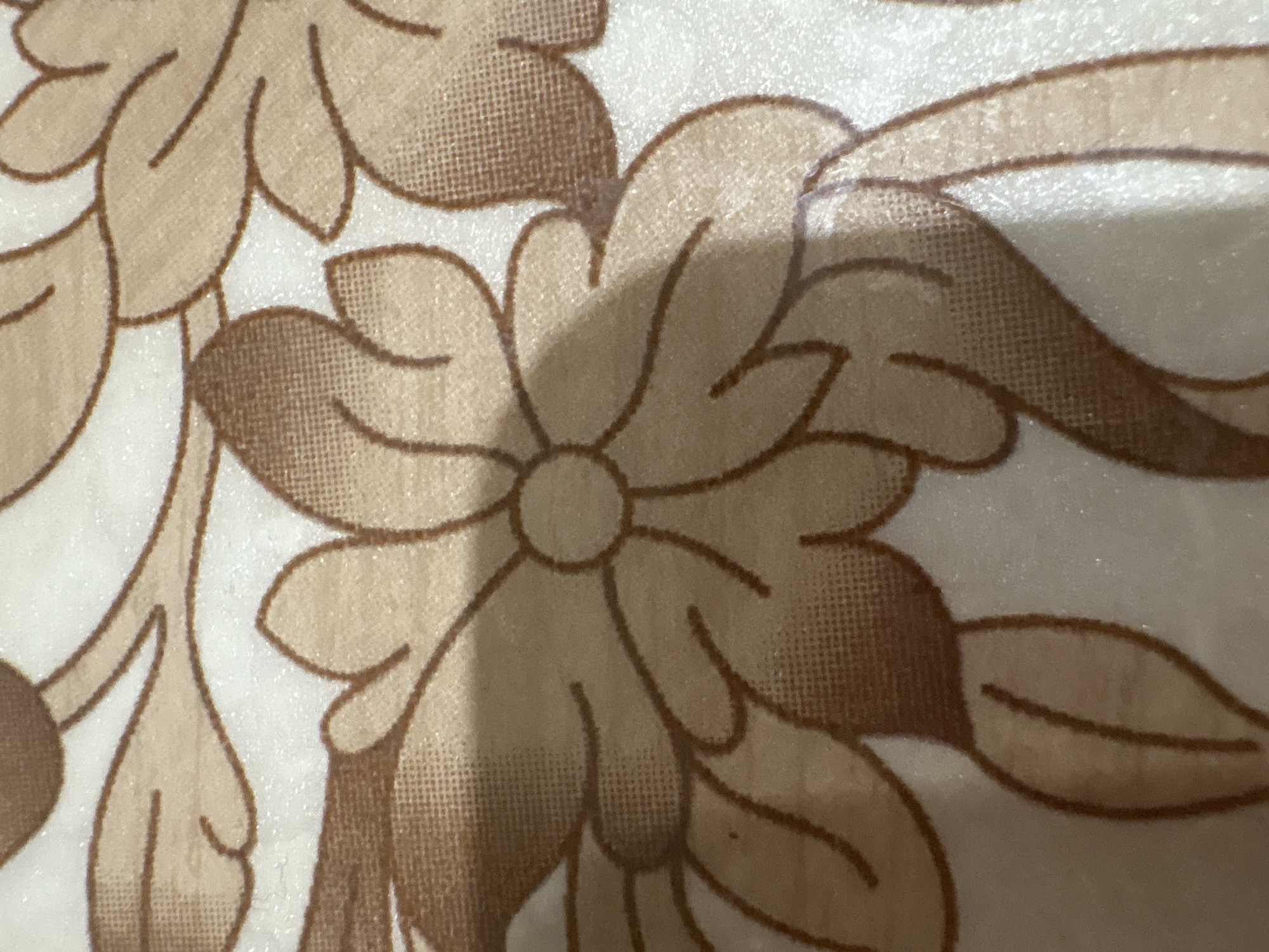 The image shows a close-up of a patterned fabric with stylized floral designs. The flowers are primarily in shades of brown and beige, outlined in a darker brown. The background is a light, off-white color. The pattern appears to be printed or woven onto the fabric. No people, actions, or environment information is present. The location of Chaikovsky, Russia is not relevant to the visible content of the image.