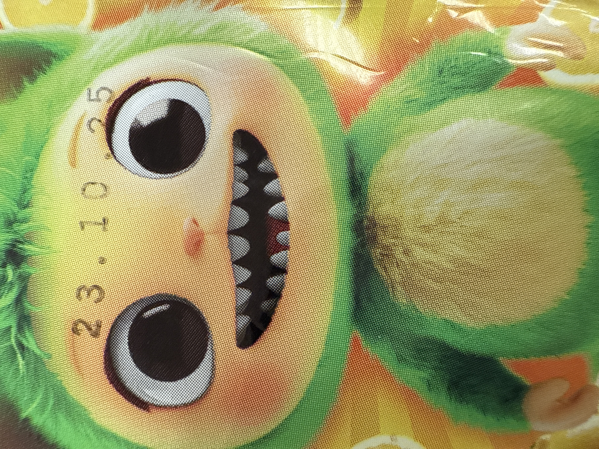 The image shows a cartoonish figure with green fur, large black eyes, and a wide mouth displaying sharp teeth. The figure's face is light yellow/tan, and the overall background appears to be a mix of yellow and orange tones. A date "23.10.25" is printed near the left eye of the character. There is no information regarding Votkinsk, Russia, or any other location.