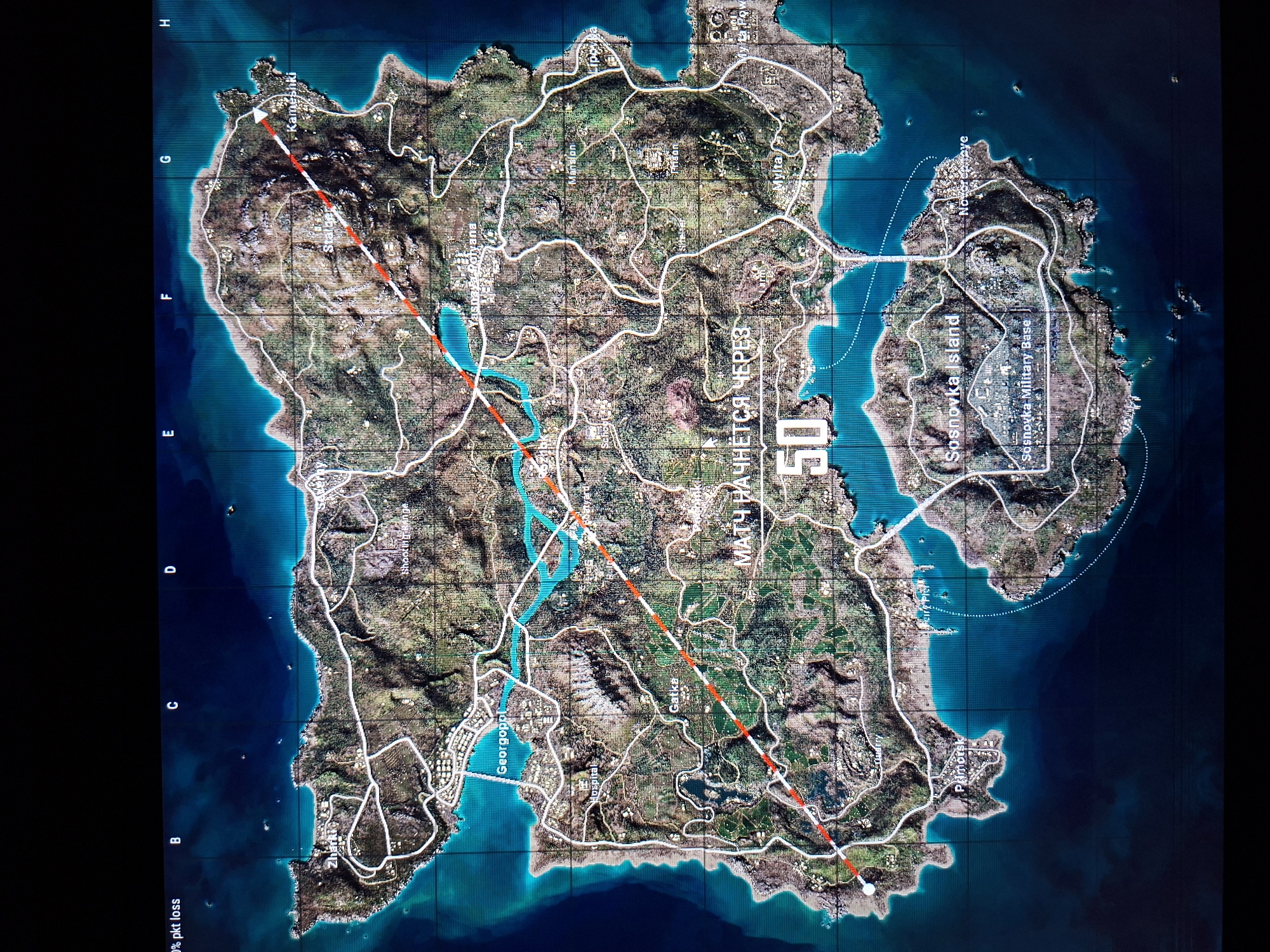 This image is a map of the Erangel map from the game PlayerUnknown's Battlegrounds. It shows the various locations, roads, and geographical features of the map. A red line spans the entire length of the Erangel map. The map is divided into a grid. The island is surrounded by water. There are land masses jutting into the water, and one separate island on the right side of the map. The island has various terrain features, including mountains, forests, and plains. The map also shows various towns and cities, such as Kameshki, Georgopol, Gatka, and Primorsk.