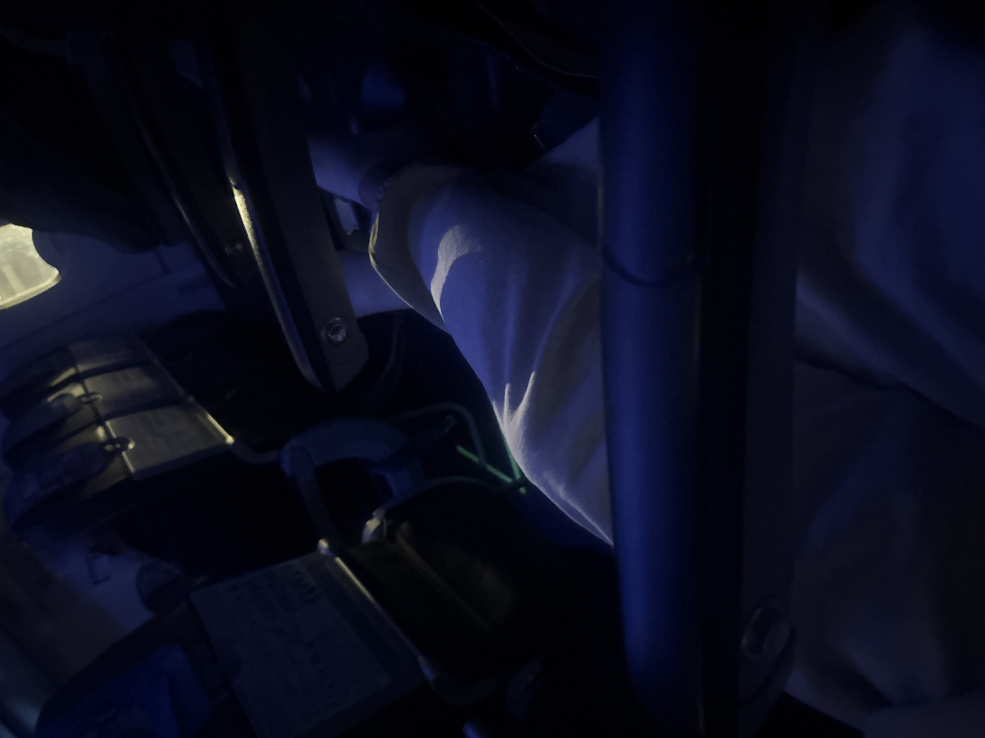 The image shows a cluttered, poorly lit interior. A light-colored sleeve is visible near the center, contrasting with the surrounding dark components. Various metallic and plastic elements are present, suggesting machinery or vehicle parts. Some components are arranged with visible bolts. Due to the lighting and depth, the specifics of the setting remain unclear. There is no clear evidence to pinpoint the location within the city of Khimki, Russia.