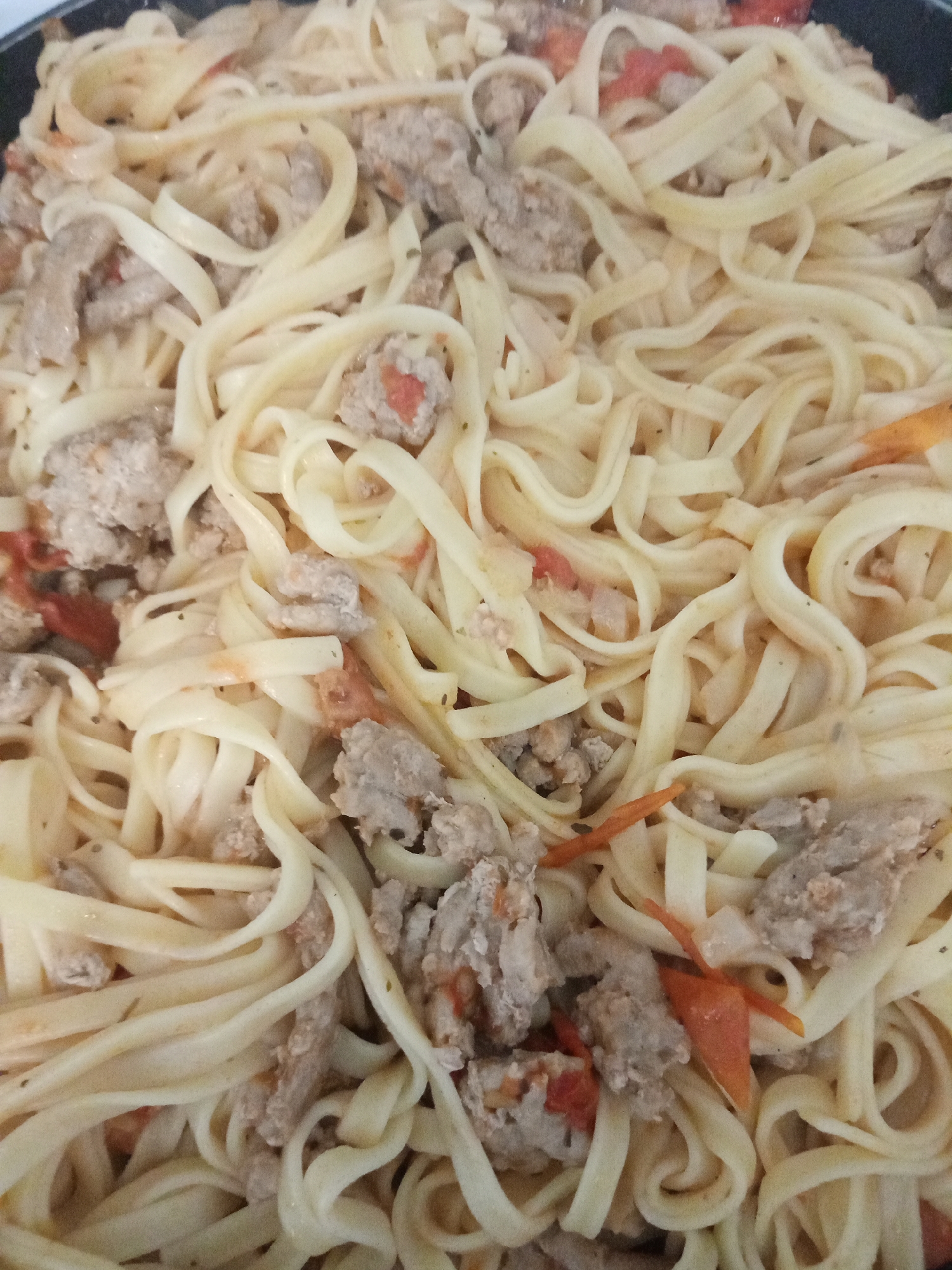The image shows a close-up view of pasta with what appears to be ground meat and tomato pieces. The pasta is a long, flat noodle, possibly fettuccine or linguine. The ground meat is scattered throughout the dish. The image does not depict a specific location in Elektrostal, Russia, nor does it contain information about people, actions, interactions, or the environment beyond the pasta dish itself.