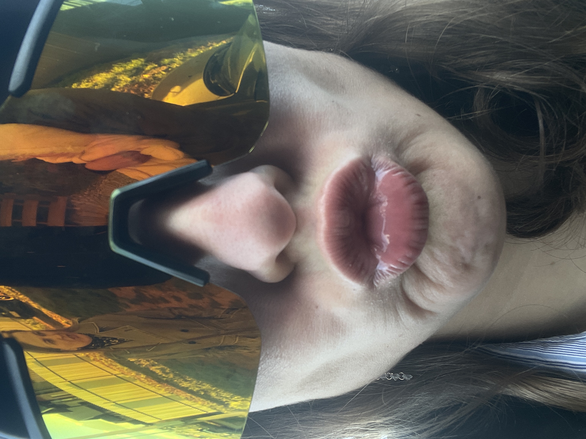 A close-up, face-level photograph shows a person's face partially obscured by golden-tinted glasses. The nose and mouth are visible. Reflected in the glasses' lenses is the image of a person wearing a jacket, likely captured within an urban environment. The person in the photograph has brown hair and appears to be wearing a striped shirt. The location in the city of Подшивалово, Russia, is not directly determinable from the image.