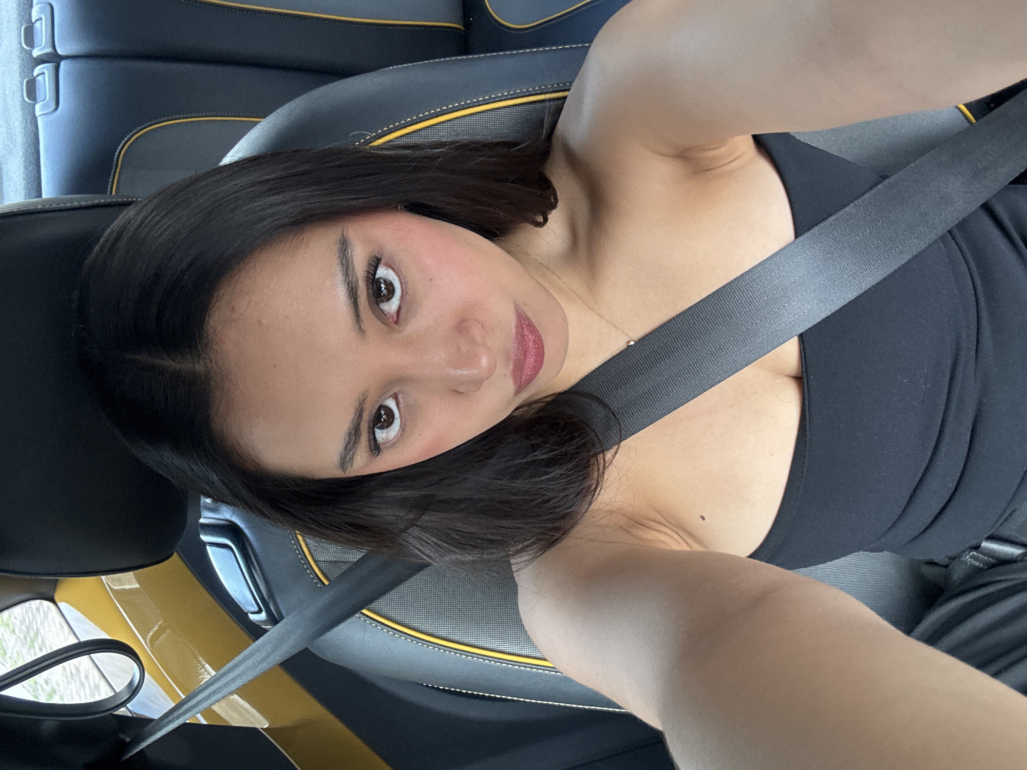 A woman with dark hair and brown eyes is wearing a black top and a seatbelt in what appears to be a car interior. The car's seats are black with yellow trim. The location is in Puebla, Mexico.