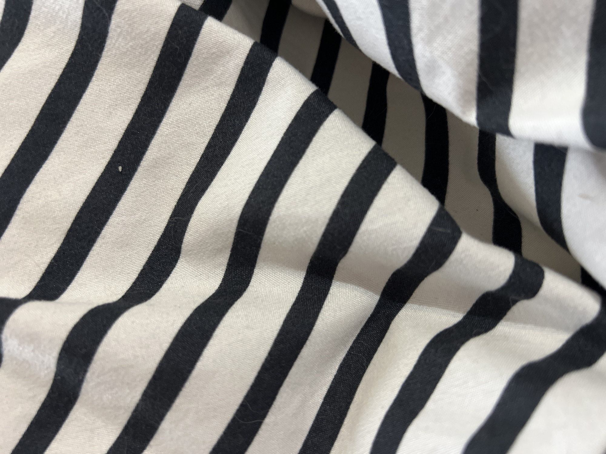 The image shows a close-up of a wrinkled fabric with black and white stripes. The stripes are of equal width and run diagonally across the frame. The fabric is likely cotton or a similar material, with a slightly shiny surface. There are no people, actions, or interactions visible. The environment is not specified. The location of Gradishte, Bulgaria is irrelevant to the provided image.