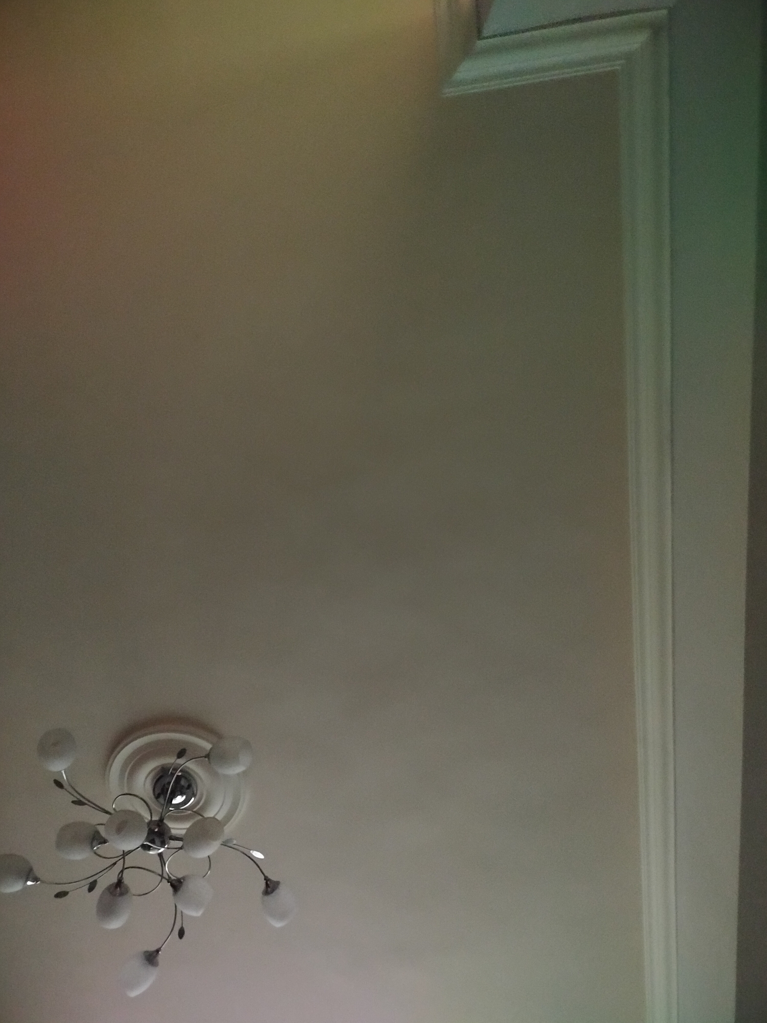 A low-angle shot of a room's ceiling, likely indoors. The ceiling is pale in color and appears smooth. A modern-style chandelier with multiple frosted glass shades extends from a decorative circular medallion attached to the ceiling. The top right corner of the image shows white molding. There are no people visible. The location (Yerevan, Armenia) is unverifiable from the image.