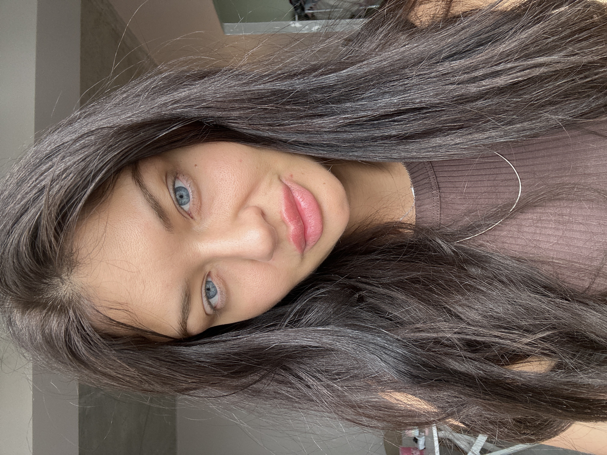 A close-up, angled headshot shows a young woman with light blue eyes and long, dark brown hair. She is wearing a brown top and a silver necklace. The background appears to be a neutral, possibly indoor setting. There is no indication that the image was taken in Khimki, Russia.