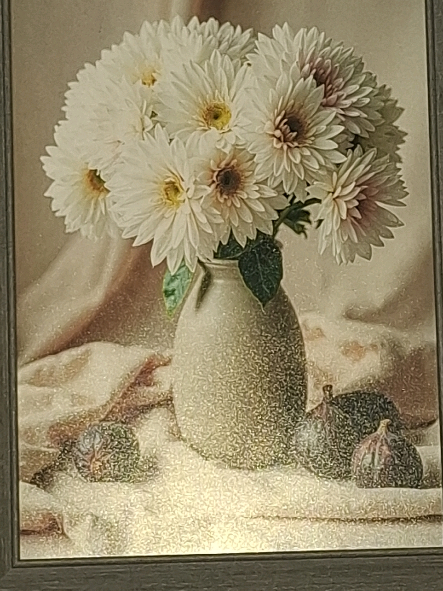 This is a still life painting featuring a bouquet of white and pink dahlias in a textured vase. The vase is positioned on a surface covered with draped fabric. In the foreground, there are two figs. The background is a soft, muted color. The artwork is framed and appears to be a traditional still life arrangement. There is no visible connection to Almaty, Kazakhstan.