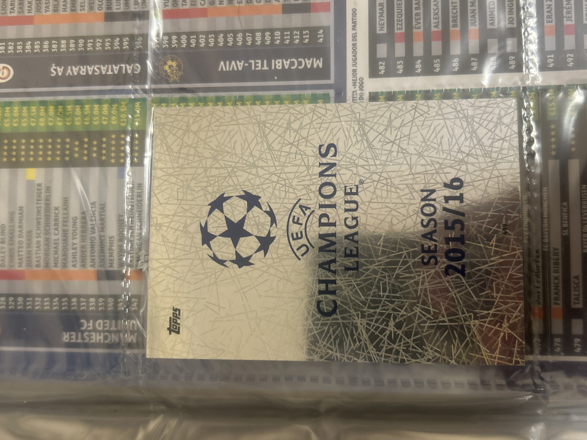 The image shows a trading card from the UEFA Champions League season 2015/16. It features the UEFA Champions League logo and the text "SEASON 2015/16." The card is from Topps, as indicated by the logo in the bottom left corner. The card is housed in a trading card binder, with other player cards visible around it, specifically ones for teams such as Manchester United, Galatasaray AŞ, and Maccabi Tel-Aviv. Cards 482-489 and 491-492 can be partially seen, as well as cards 478 and 479. The location of Pleven, Bulgaria is not present in the image.