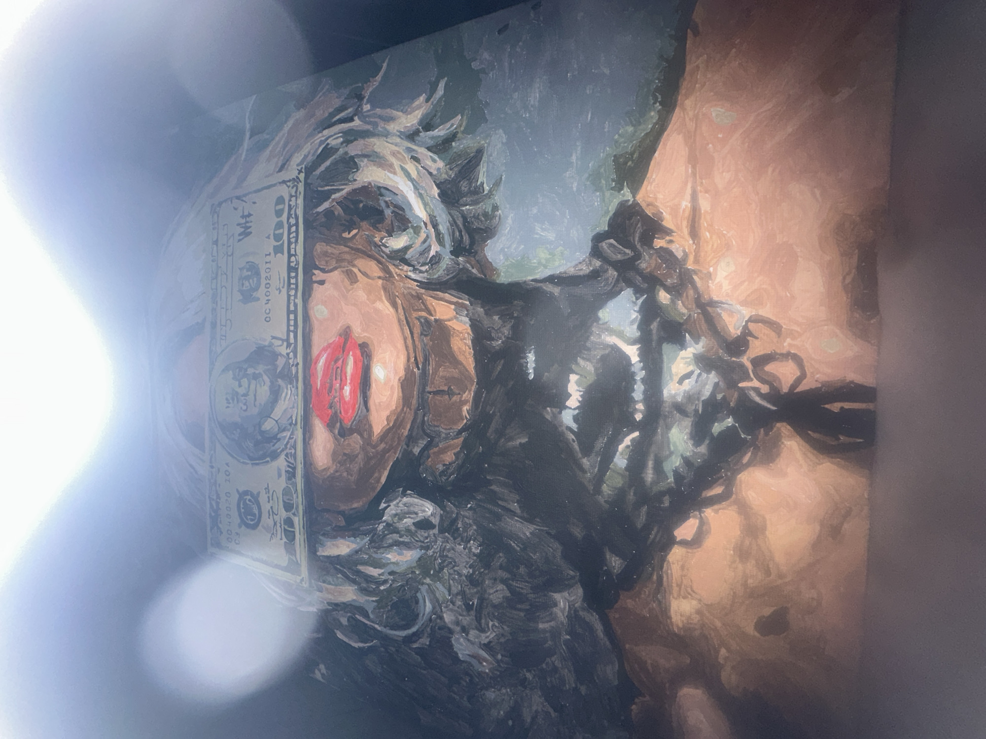 The media file displays a rotated photograph of a painting, depicting a close-up of a person's face. A $100 bill is centrally placed over the person's eyes, completely obscuring them.
The visible facial features include a prominent nose, full red lips, and a chin. Dark, textured hair, possibly dreadlocks or braids, frames the face, particularly around the temples and jawline. The skin tone is warm, appearing tan or light brown, rendered with visible brushstrokes characteristic of an oil or acrylic painting. The background is dark and indistinct, focusing attention on the figure.
On the $100 bill, the number "100" is clearly visible in the top right corner. A portrait (likely Benjamin Franklin's) is also discernible on the left side of the bill. Visible text includes "QC002011" and "WF" which appear to be parts of a serial number or plate number.
The photograph itself has significant bright light flares on the left side, partially obscuring the left portion of the artwork, including part of the $100 bill and the left side of the person's face and hair. These flares suggest the picture was taken of a screen or a reflective surface, rather than directly of the artwork under controlled lighting. The painting's original orientation appears to be portrait, but the photograph is taken in landscape, rotated 90 degrees counter-clockwise.
