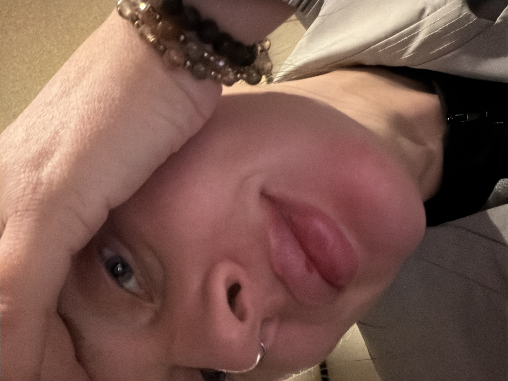 A close-up, angled shot focuses on a person's face. The person's hand, adorned with a beaded bracelet, is positioned on their forehead. The person has blue eyes, a nose ring, and is sticking out their tongue. They are wearing a black top under a light-colored jacket.
The image does not contain visual information indicating a location in Moscow, Russia.