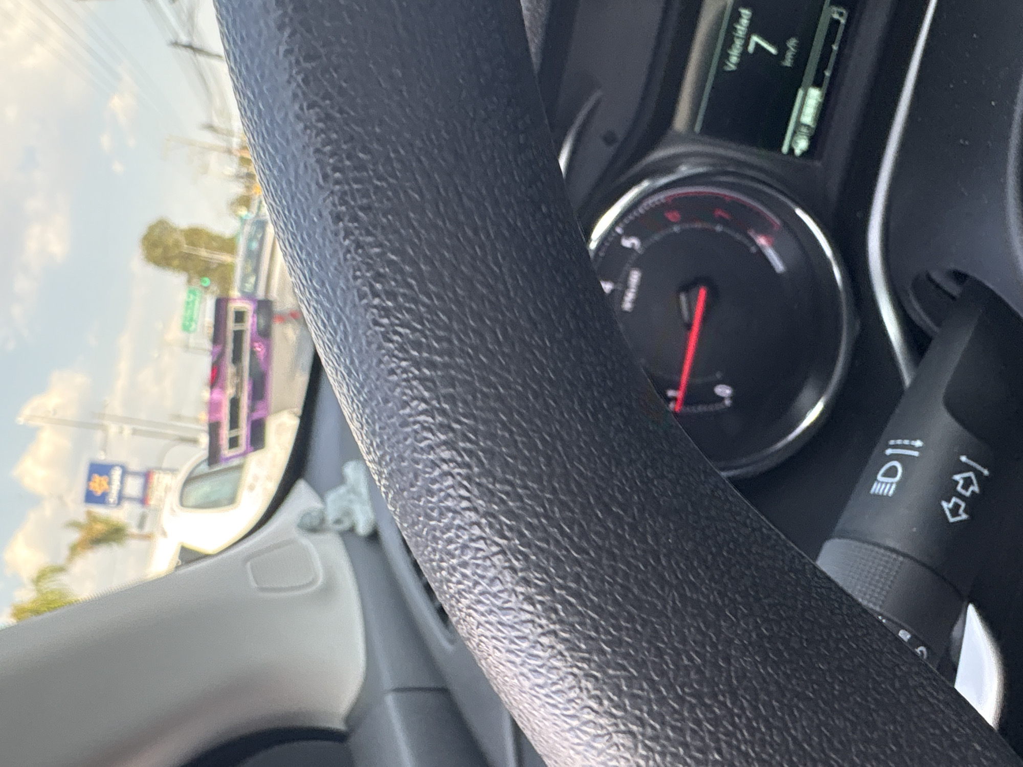The image depicts the interior of a car, specifically the steering wheel and dashboard. The speedometer indicates the car is moving at 7 km/h. Through the windshield, a blurry view of a city street is visible, including a Walmart sign. The location is inferred to be in Puebla, Mexico.