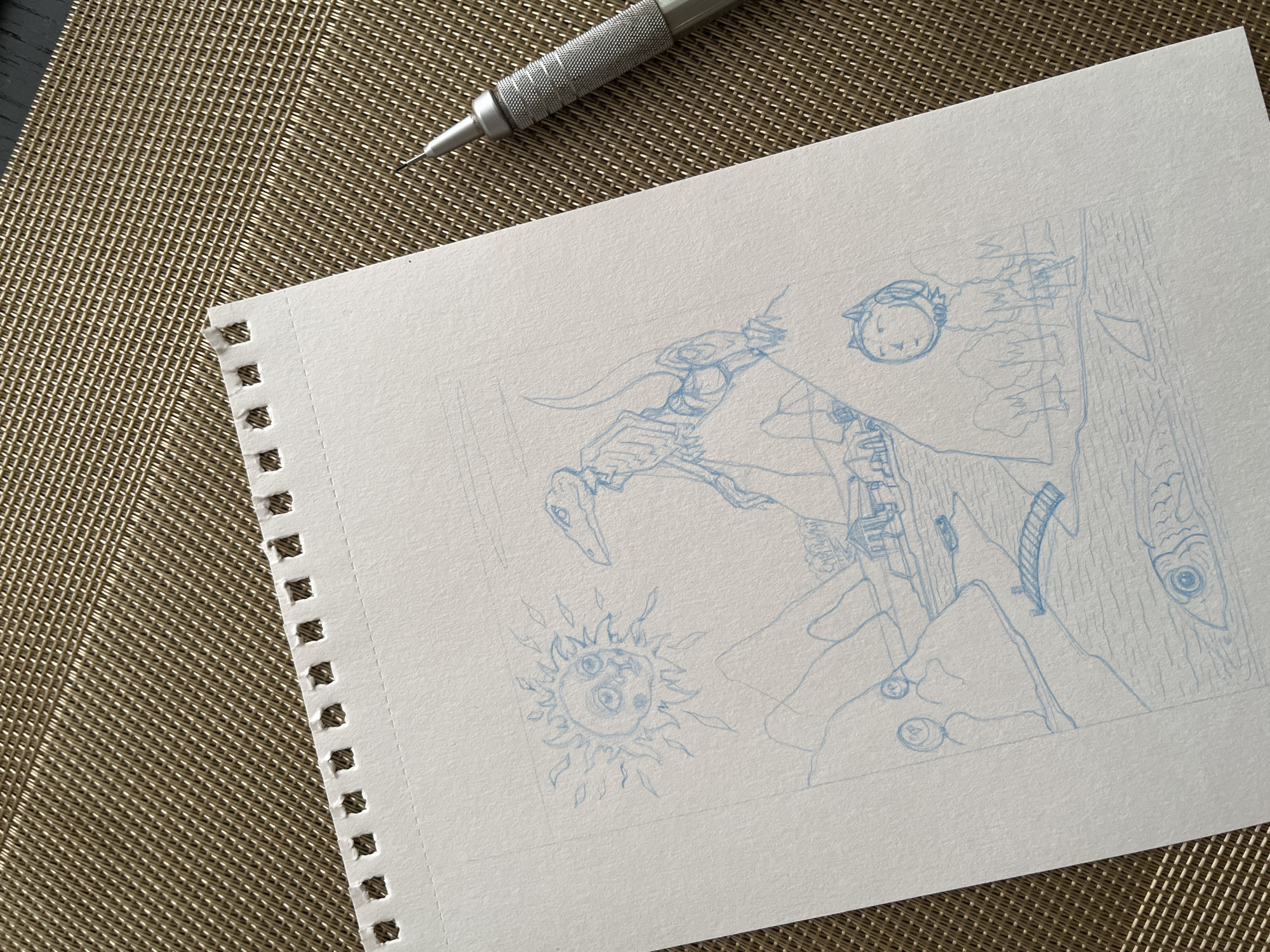The image displays a sketch on a piece of paper, featuring a surreal landscape with a dinosaurlike creature and a sun with a face. There are also elements of a town or village with buildings and a bridge over water. A fish is depicted in the water below, and a shark fin is visible. In the foreground, there are two figures, one resembling a person with a cat's ears and another abstract figure. The sketch is done in blue pencil. The paper is placed on a textured brown surface, likely a placemat. A metal drafting pencil is partially visible on the right side of the image. There is no identifiable information within the sketch or its surrounding context that relates to the city of Krasnoyarsk, Russia.