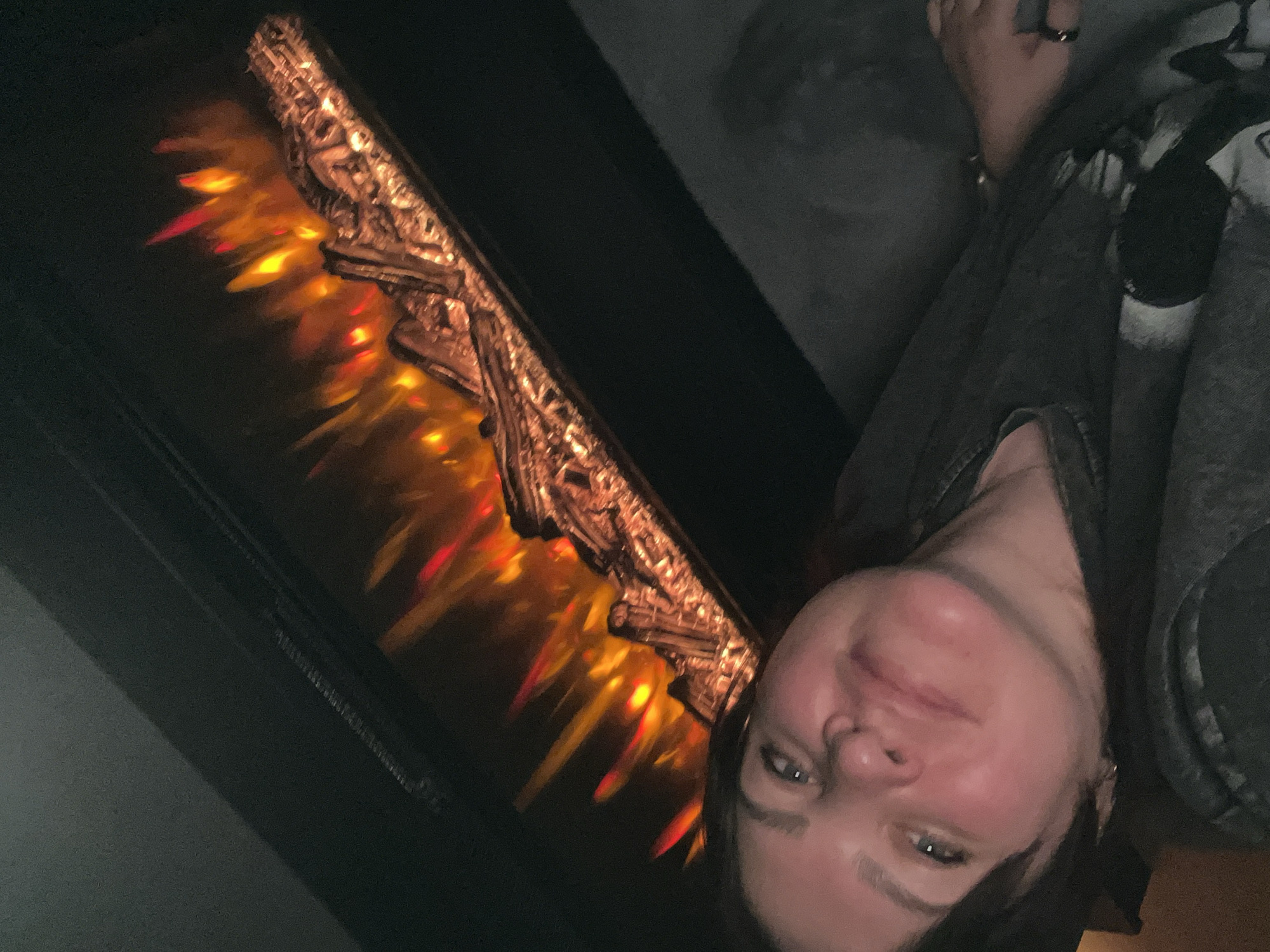 A woman poses in front of what appears to be a decorative fireplace with imitation flames. The location and its relationship to Perm, Russia, cannot be determined from the visual data.