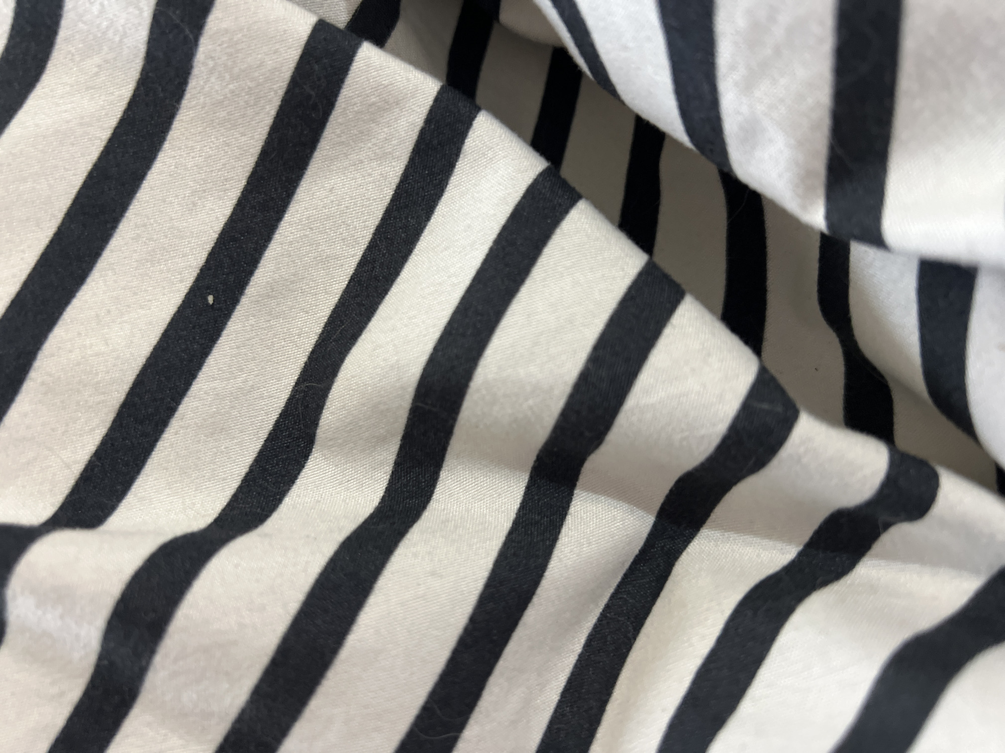 This is a close-up image of a piece of fabric with black and white stripes. The fabric is wrinkled and folded, creating shadows and highlights that emphasize the texture. The stripes run diagonally across the frame. The image provides no information about Gradishte, Bulgaria or its surroundings.