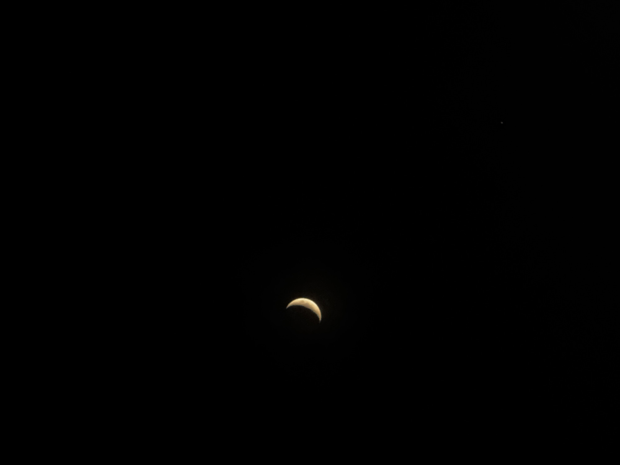 A waxing crescent moon is visible in the dark night sky. A single star is also visible in the upper right portion of the frame. The image does not provide enough information to determine the location of Kazan, Russia.