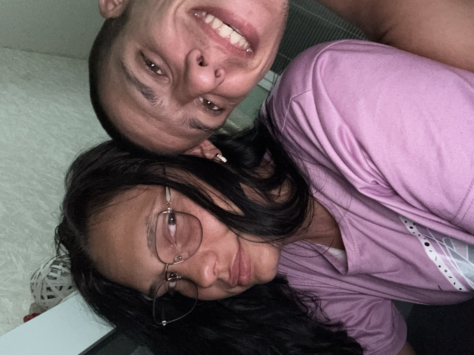 Two people are in the image, a woman with long dark hair and glasses wearing a purple shirt, and a man. The man is upside down. The image is taken indoors. The location in Sofia, Bulgaria cannot be determined from the visual data.