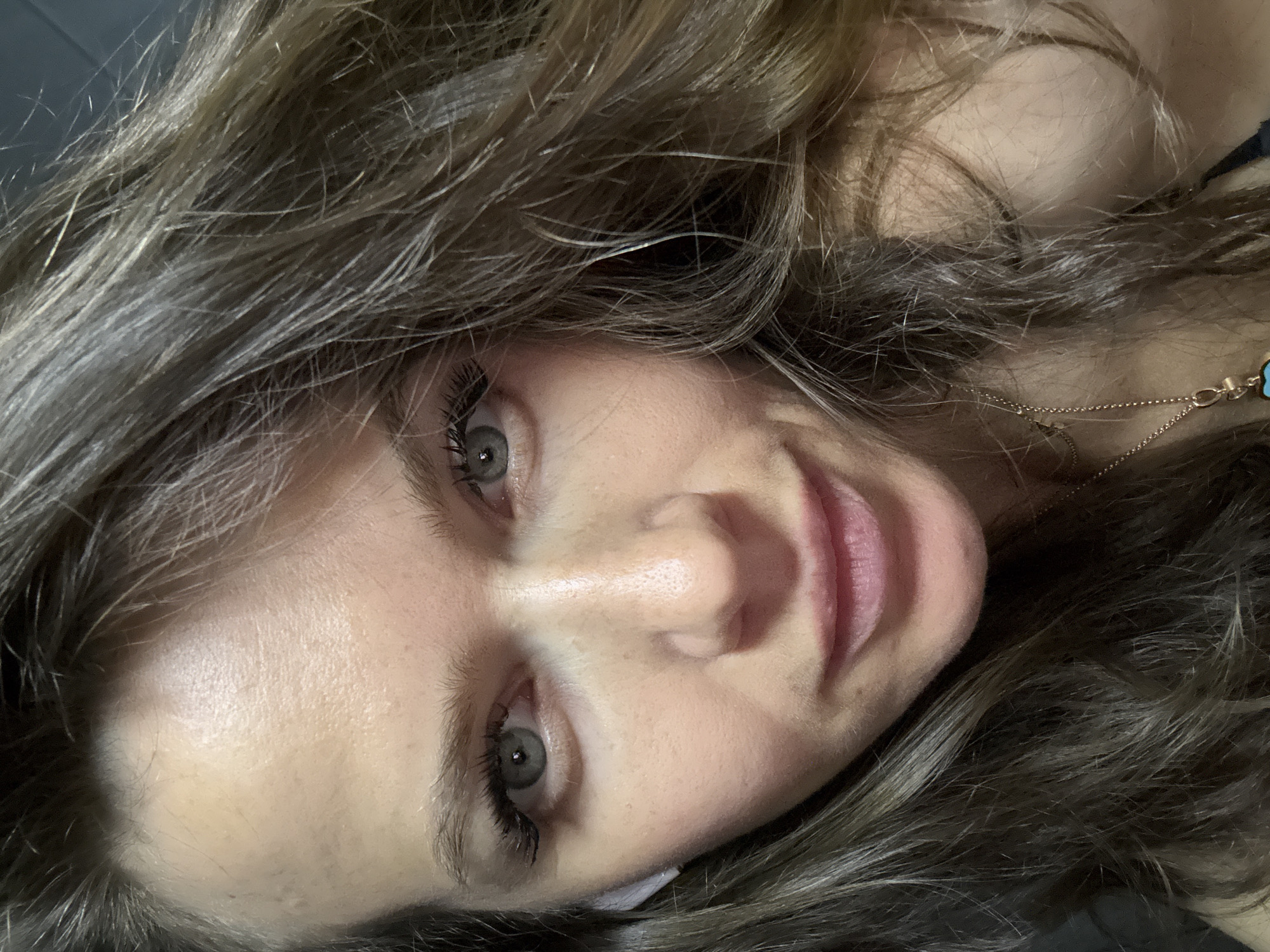 A close-up, slightly angled portrait of a woman with light skin and light brown hair. She has light-colored eyes and well-defined eyelashes. A gold necklace is visible around her neck. The background is blurred and out of focus. There is no information to support the location in the city of Khimki, Russia.
