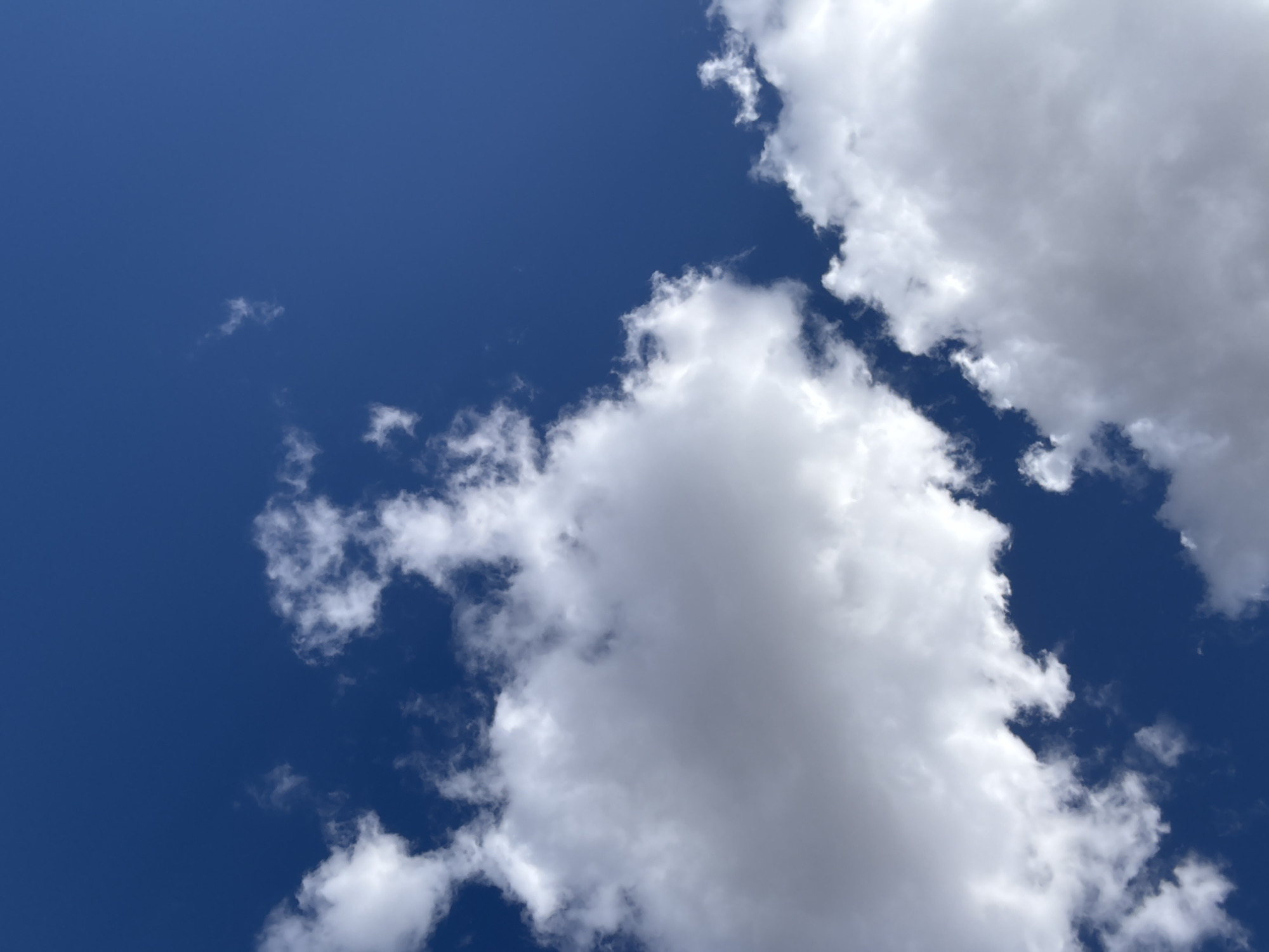 The image shows a bright blue sky with several white clouds. The clouds vary in size and density, with some appearing fluffy and others more wispy. The sky is clear and deep blue in areas without cloud cover. The image was taken in Klin, Russia, but no element in the picture specifically confirms that.