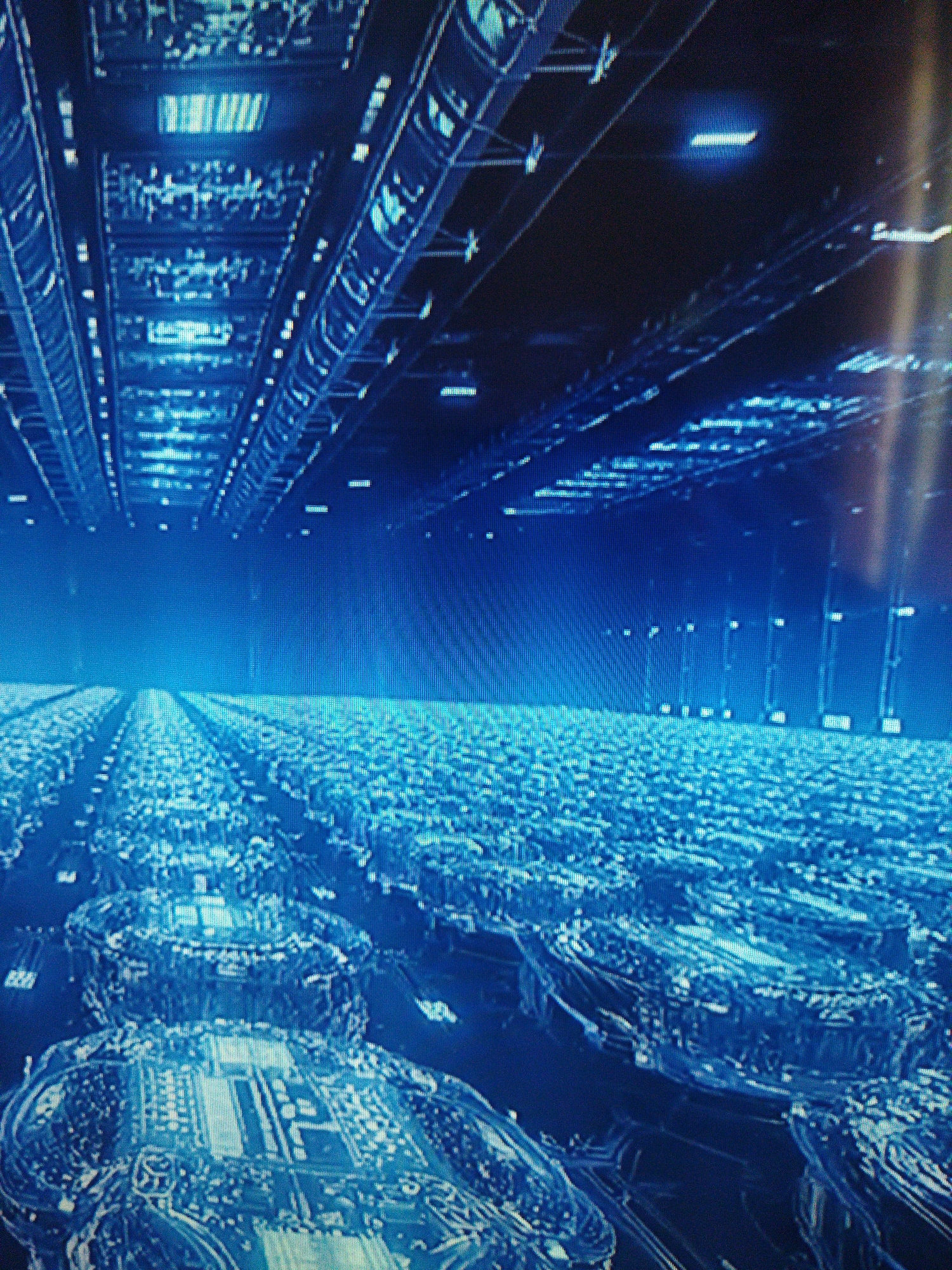 The image depicts an expansive server farm, characterized by rows of computer servers stretching into the distance, illuminated by overhead fluorescent lighting. The servers are dark blue. The ceilings are dark, with linear rows of lights. The environment appears to be a high-tech data center, likely used for data processing and storage. There is no visual confirmation of the city of Kramatorsk, Ukraine, nor are any people, subjects, actions, or interactions visible within the frame.