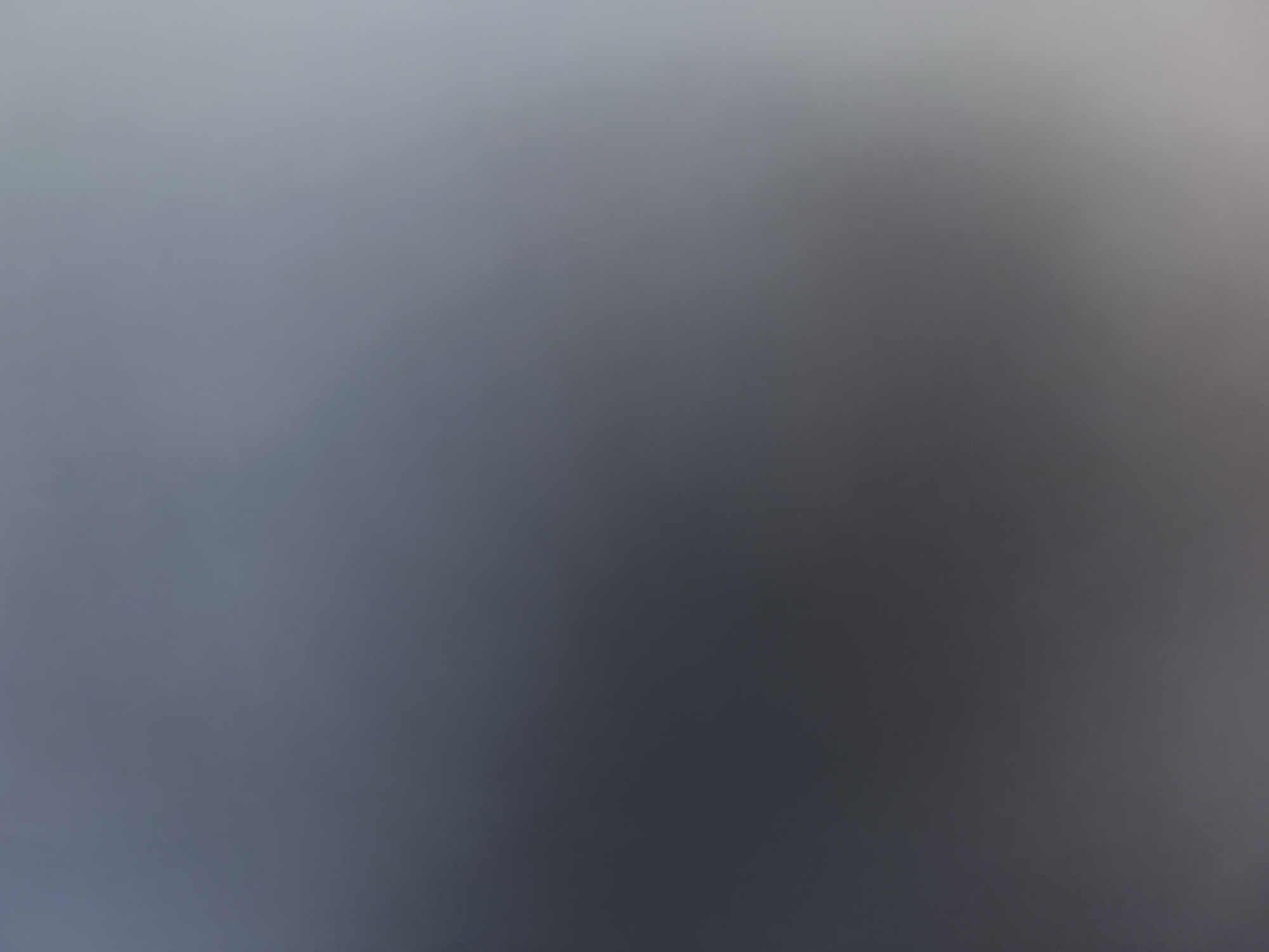 This is a very blurry, abstract image dominated by shades of grey and white. There are no discernible subjects, objects, scene, or setting. No activity or event is taking place. There are no notable details such as time of day, weather, location cues, or emotions. No text is visible. The image appears to be a result of a camera malfunction or intentional blur.