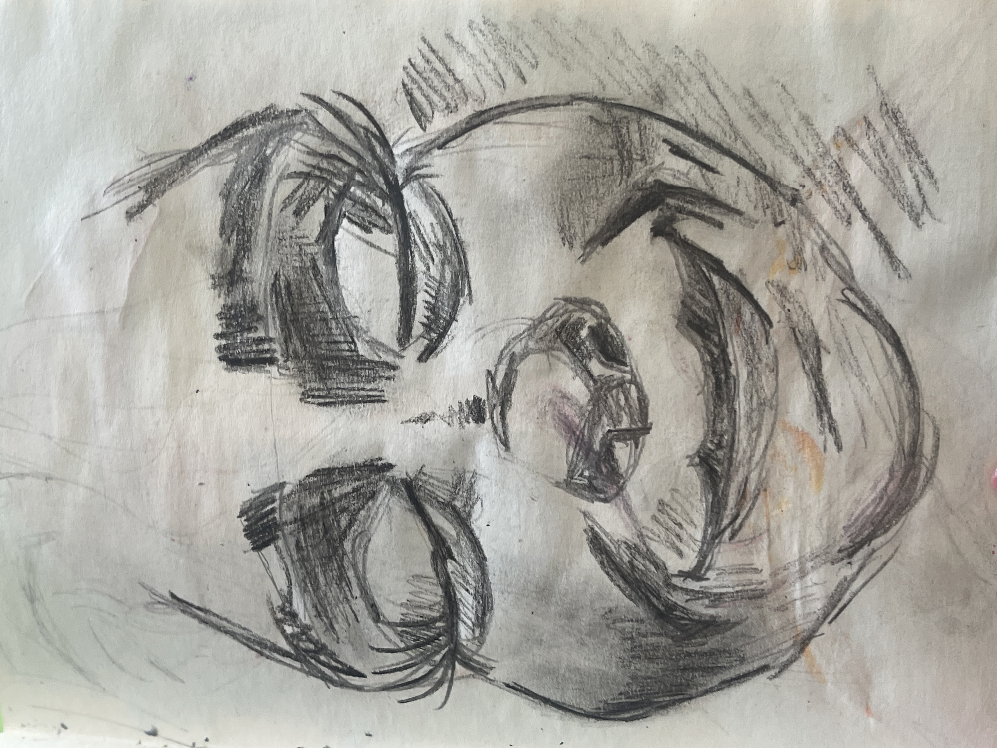The media file displays an abstract, expressive drawing of a human or humanoid face, rendered primarily in charcoal or a dark pencil on a piece of light-colored paper. The drawing is characterized by bold, thick lines and heavy, textured shading, which create a sense of depth and intensity. The visible strokes contribute to a dynamic and somewhat raw aesthetic.
The facial features are highly stylized and distorted, rather than realistically proportioned. Two prominent, almond-shaped forms, possibly representing eyes, are heavily shaded. A smaller, abstract shape suggestive of a nose or mouth is positioned centrally on the face. The overall form of the head or face appears elongated and is oriented diagonally across the paper.
The color palette is predominantly grayscale, featuring deep blacks and various shades of gray against the lighter background of the paper. Subtle, faint hints of purple/pinkish and yellowish/orange hues are visible in some areas, possibly from smudges or discoloration on the paper. The paper itself shows some signs of wear, including creases and faint marks. No text is visible in the image. The drawing conveys a sense of introspection or raw emotion through its heavy shading and abstract form.