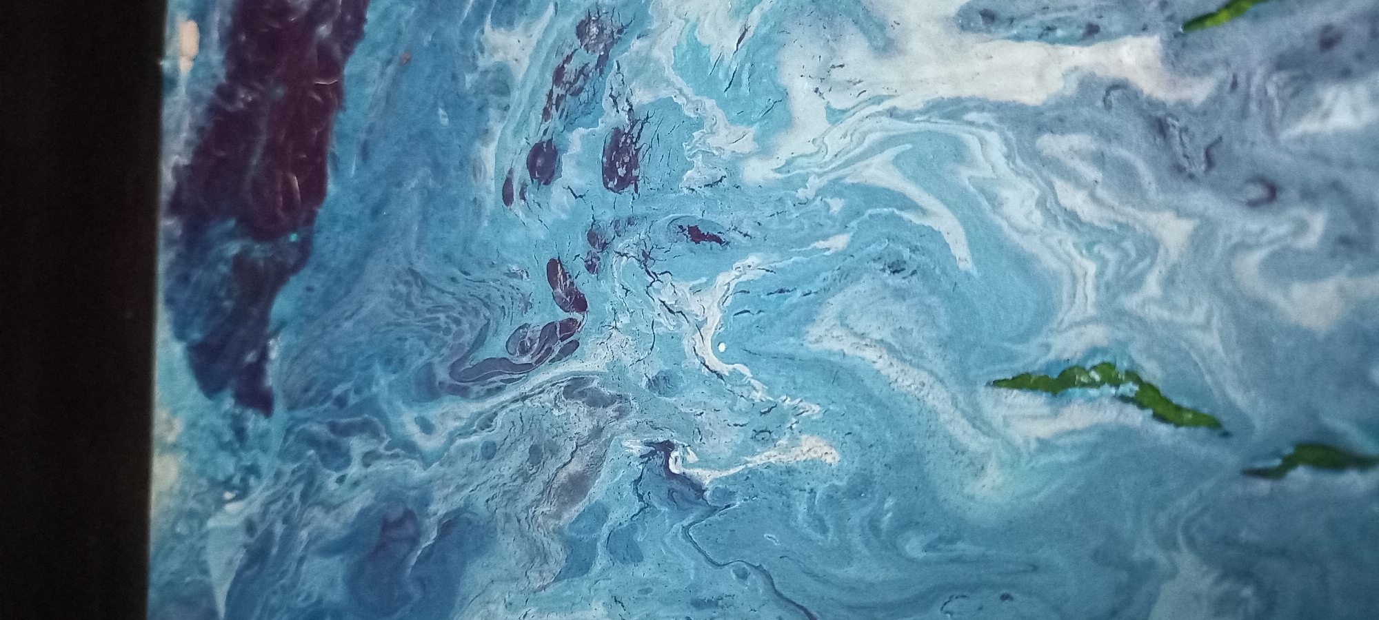 This is an abstract acrylic pour painting. The primary subjects are swirls and marbling of blue and white paint, with hints of dark red and green. The composition suggests a fluid, dynamic scene, possibly evoking water, clouds, or celestial formations. There are no people, recognizable objects, or specific setting elements. The textures created by the paint are a prominent detail, with cracks and varied opacity adding depth. The overall mood is one of movement and natural fluidity. No text is visible. The location context of Kryvyi Rih, Ukraine, is not visually represented in the artwork itself.