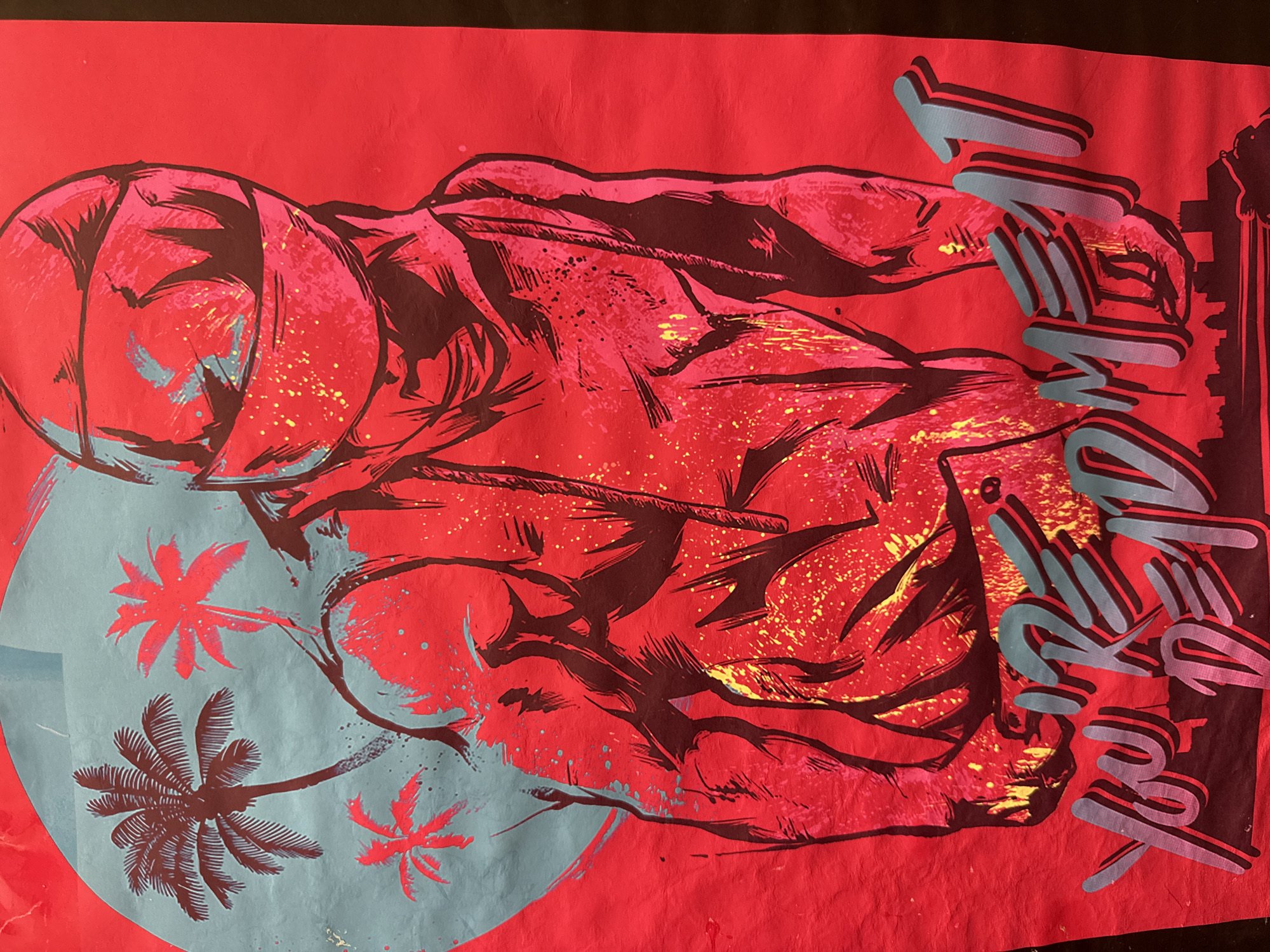 The image is a close-up, vertical shot of a poster with a bright red background. The poster depicts a stylized, muscular figure wearing a helmet that covers the entire head and face, with only dark lines suggesting facial features. The figure is rendered in shades of pink and red with black outlines and some yellow splatters. To the left of the figure, a light blue shape resembling a heart or a large circle contains silhouettes of three palm trees. The bottom of the poster features large, stylized, grey text with a pink and red shadow that reads "YOU'RE DEAD MEAT." Below the text, a dark silhouette of a city skyline is visible. The poster appears to be made of paper and shows some wrinkles and imperfections. The scene depicted is a graphic illustration and does not contain any elements that could be used to identify a specific location in Reppolovo, Russia.